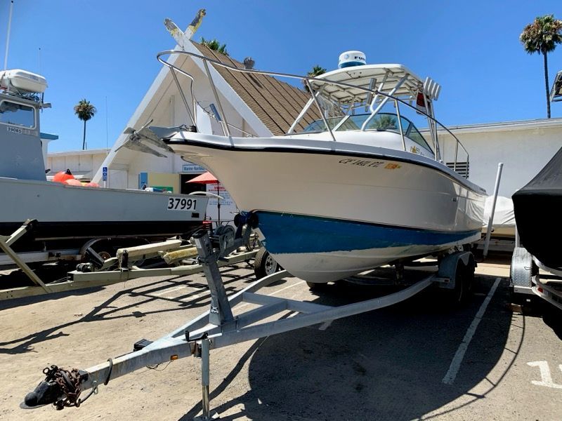 A 2003 Bayliner Walk Around Cuddy Cabin boat on a trailer in a sunny marina.