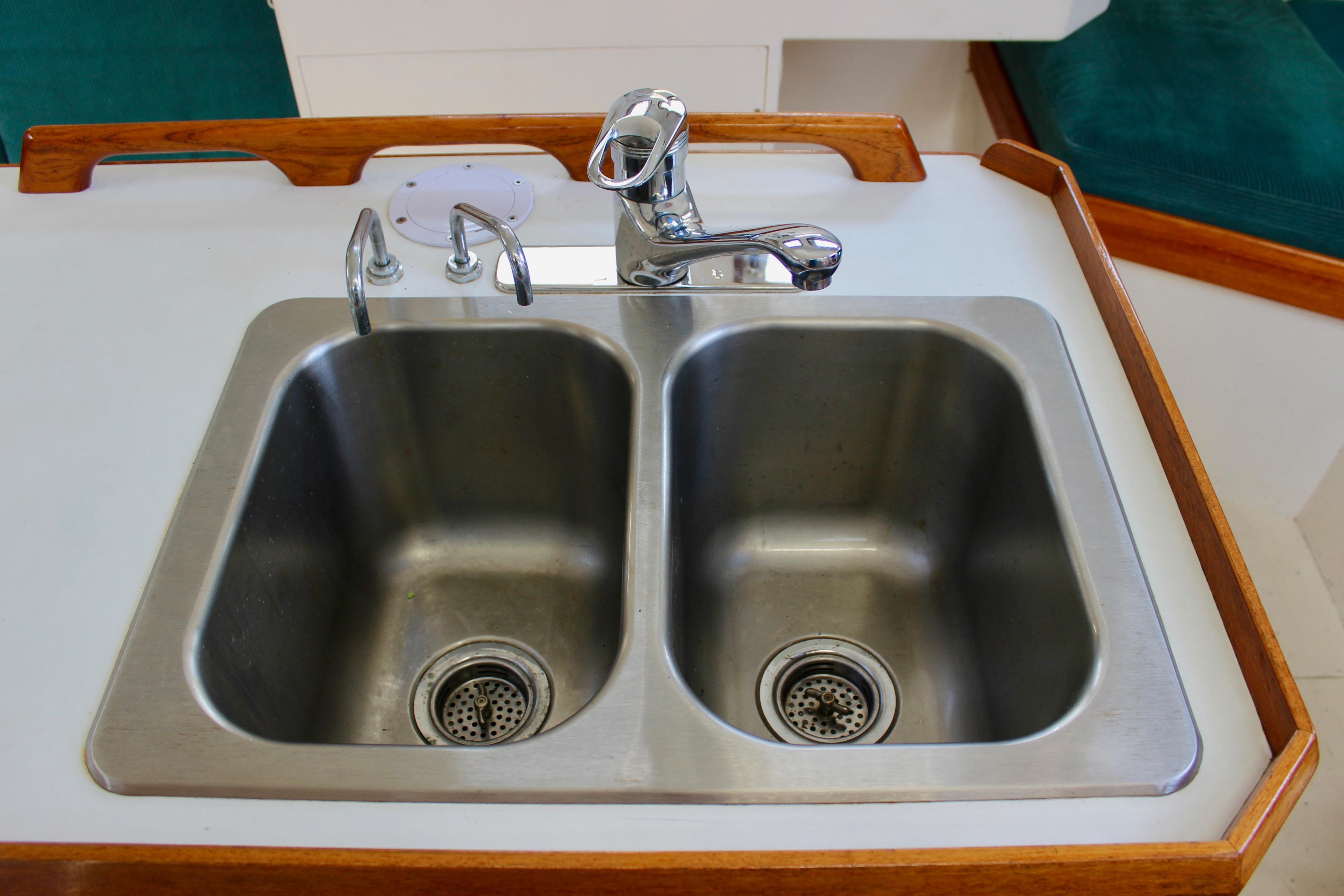 Double stainless steel sink on a 1993 Freya 39 yacht with wooden trim.