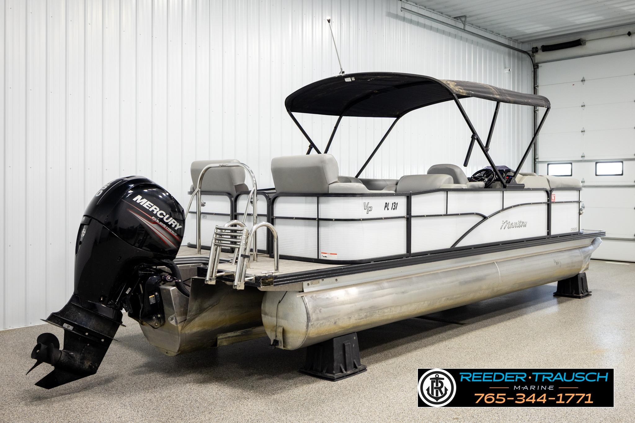 2019 Manitou Oasis SR VP pontoon boat with Mercury outboard motor in indoor storage.