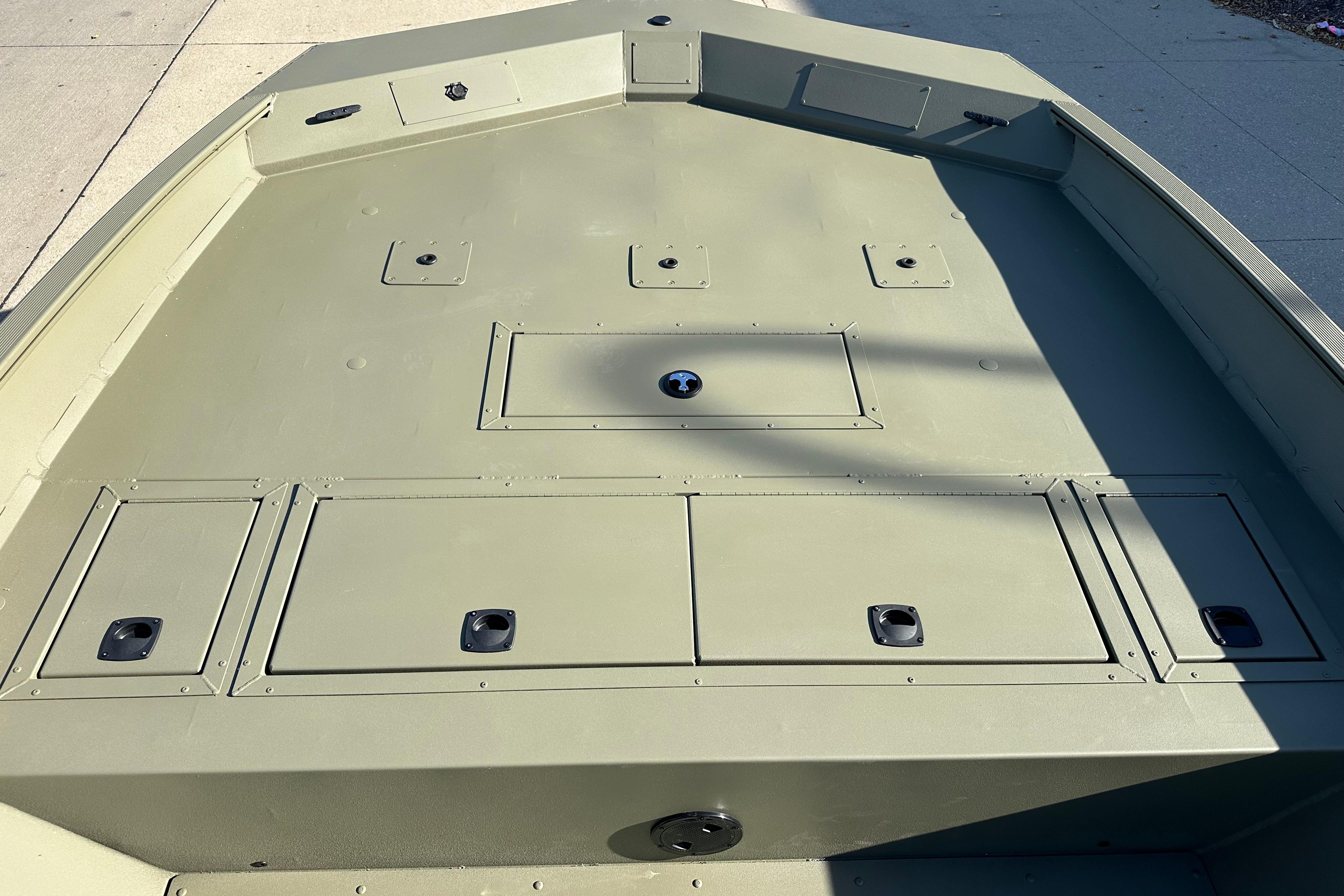 2026 Tracker Grizzly 2072 CC boat deck with storage compartments, shown in sunlight.