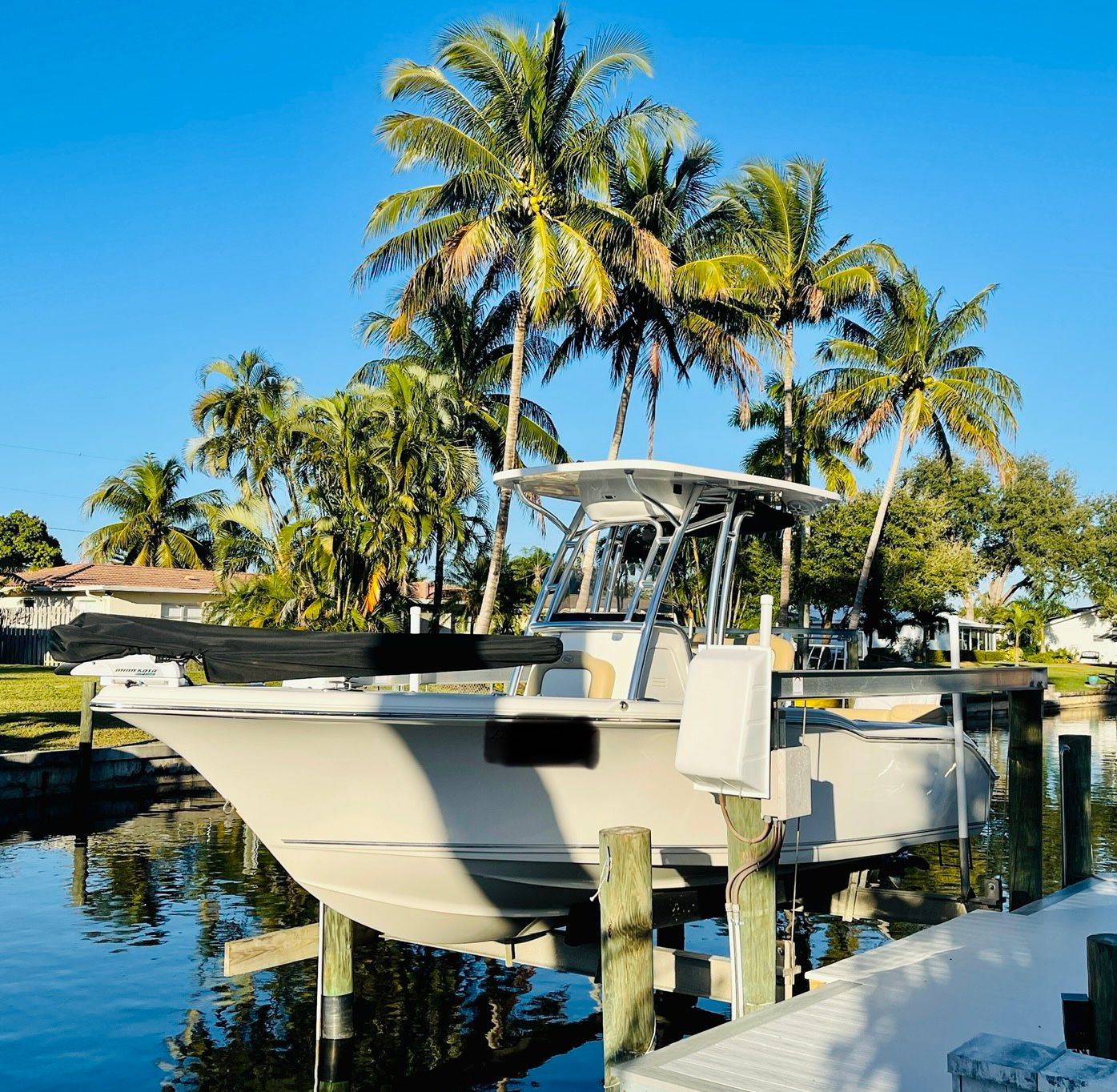 A 2018 Key West 239 FS boat docked in a sunny area, surrounded by palm trees.