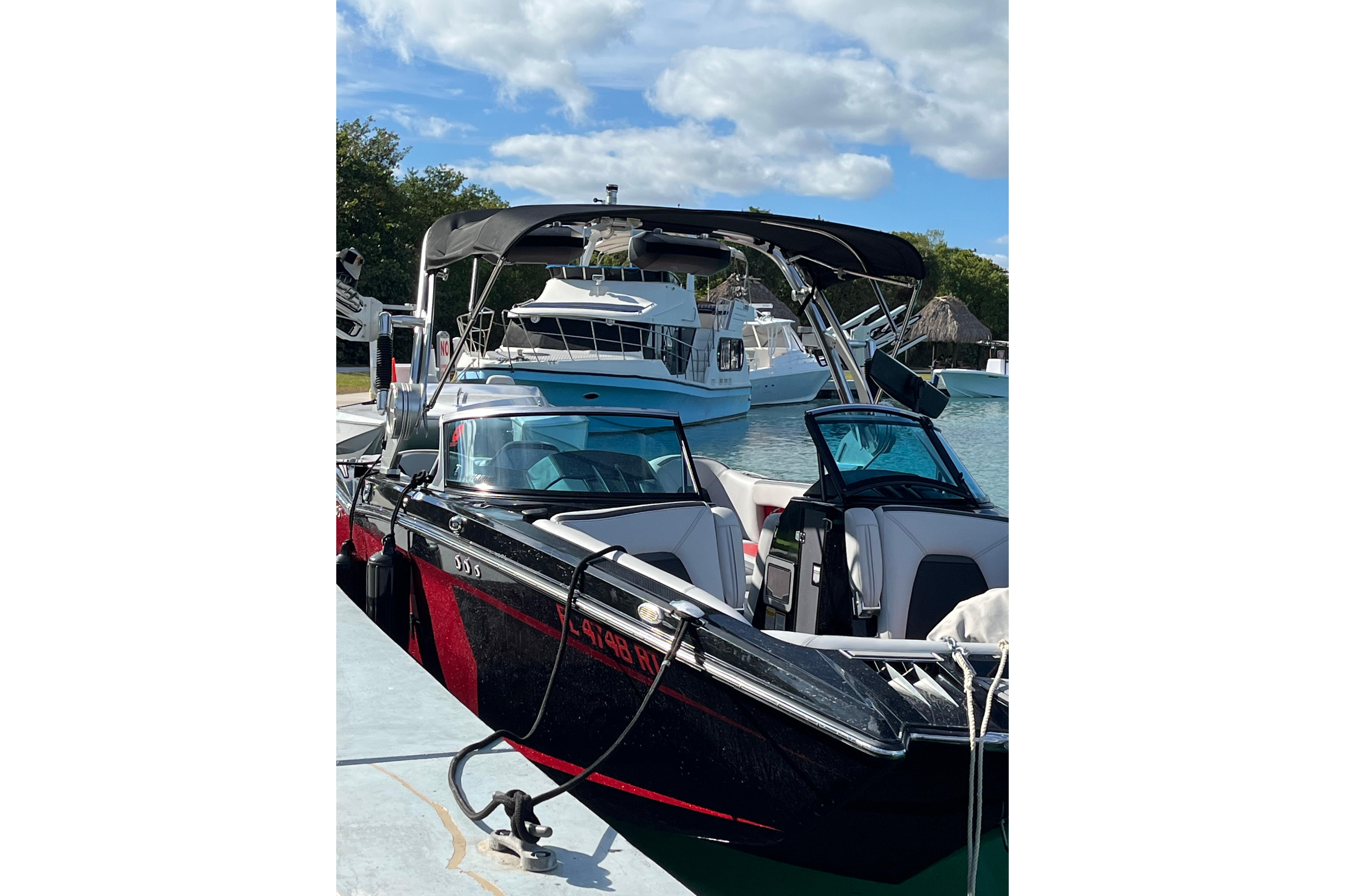 2019 MasterCraft XStar boat docked, featuring sleek black and red design under a clear sky.
