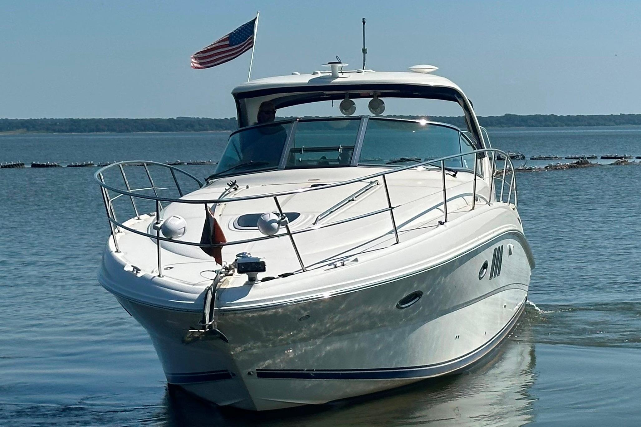2007 Sea Ray 38 Sundancer yacht cruising on calm waters with American flag.
