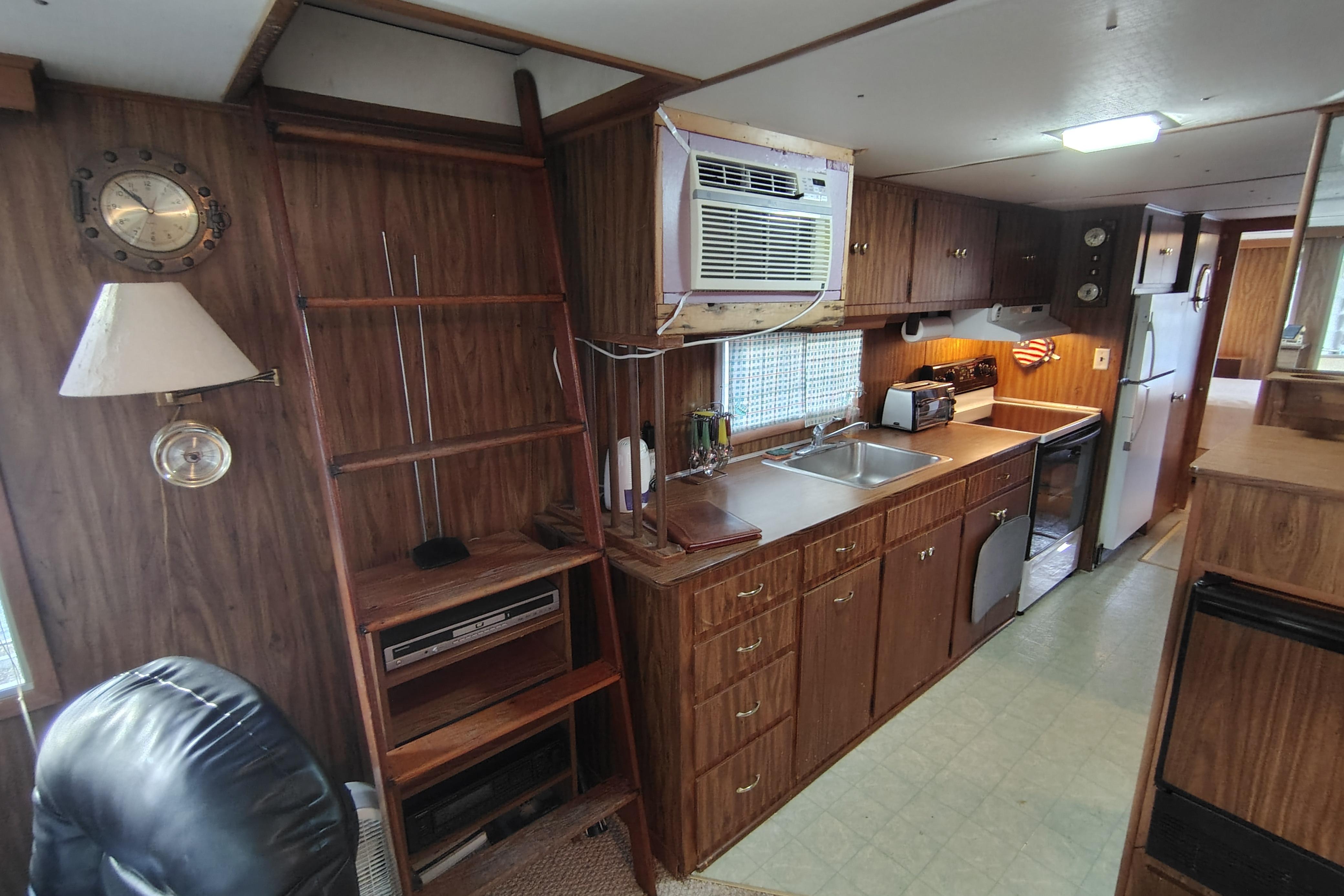 Interior of 1981 Lazy Days 50 houseboat with wood paneling and compact kitchen.