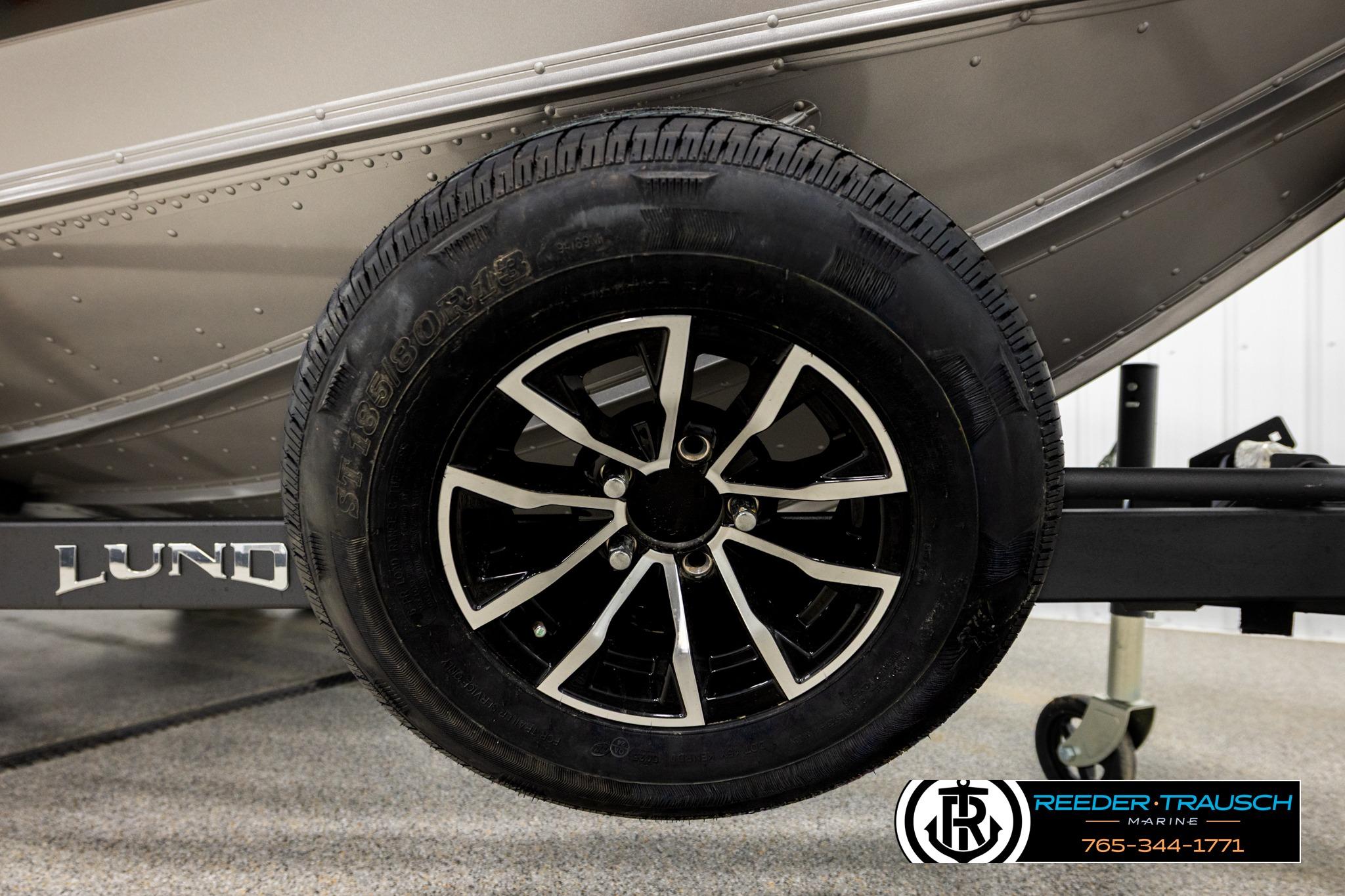 Close-up of a 2026 Lund 1975 Tyee boat trailer wheel, featuring sleek black and silver design.