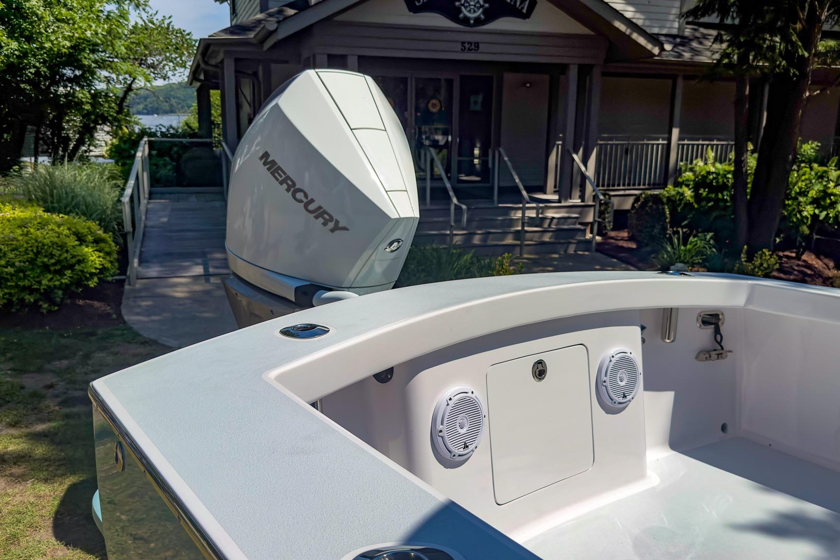 Weaver 25 boat with Mercury engine docked near a lakeside house, 2025 model.