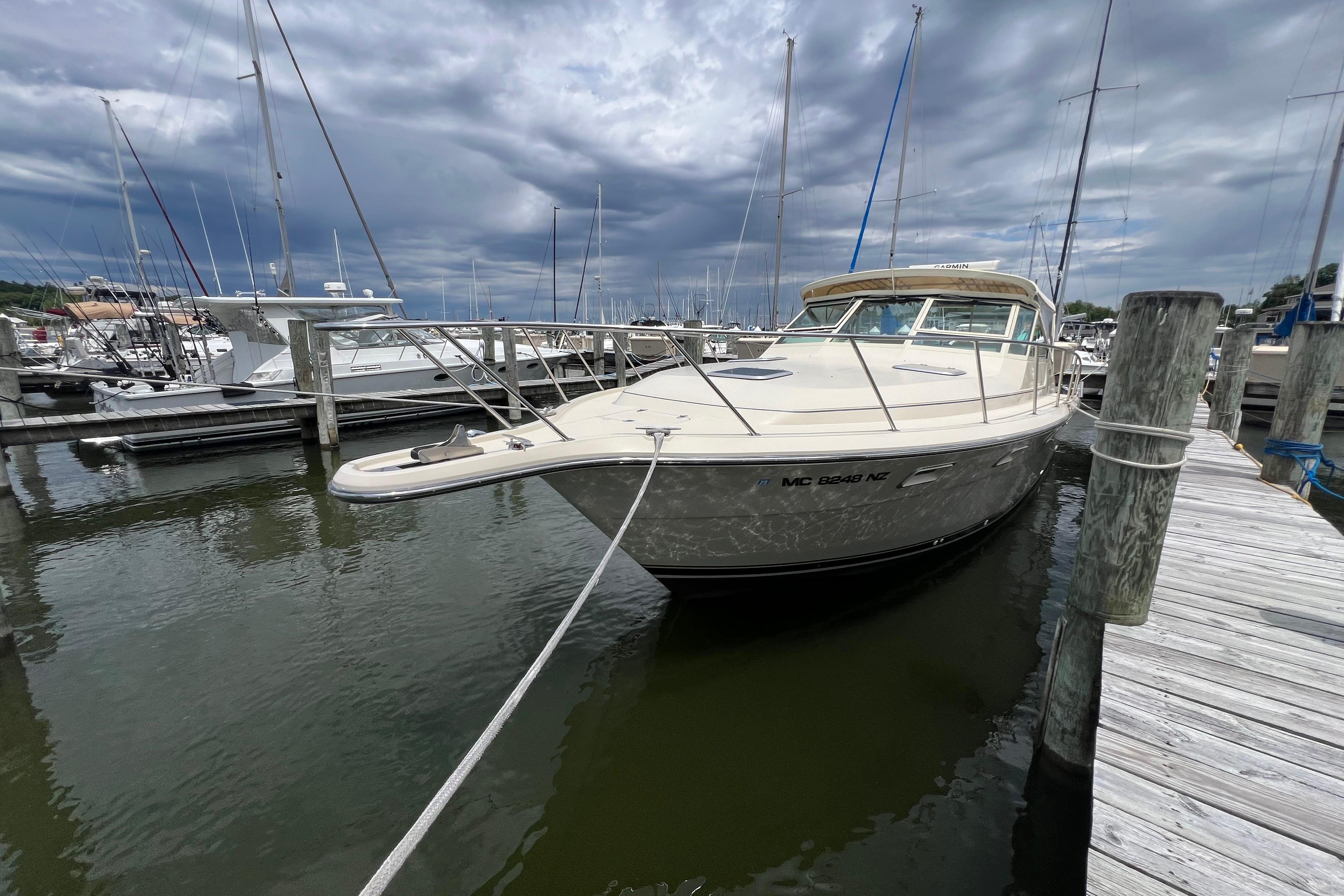 1985 Tiara 36 OPEN boat docked at marina under cloudy sky.