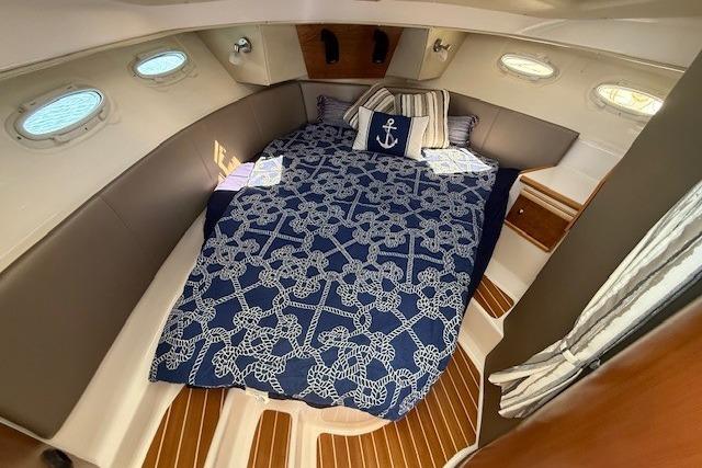 2023 Cutwater C-30 Sedan cabin with nautical-themed bedding and elegant wood flooring.
