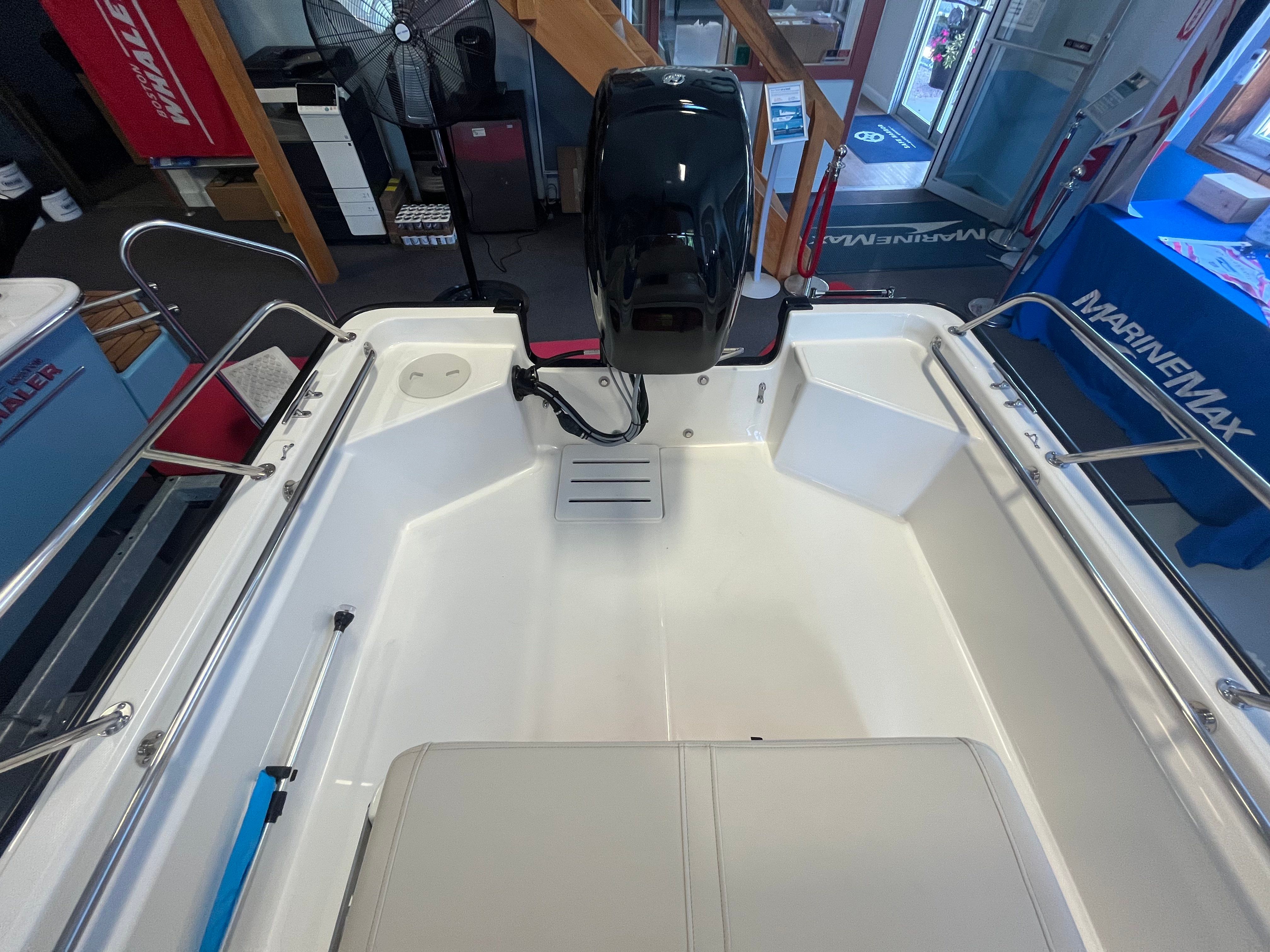 Interior view of a Boston Whaler 150 Montauk with a clean, white deck and outboard motor.
