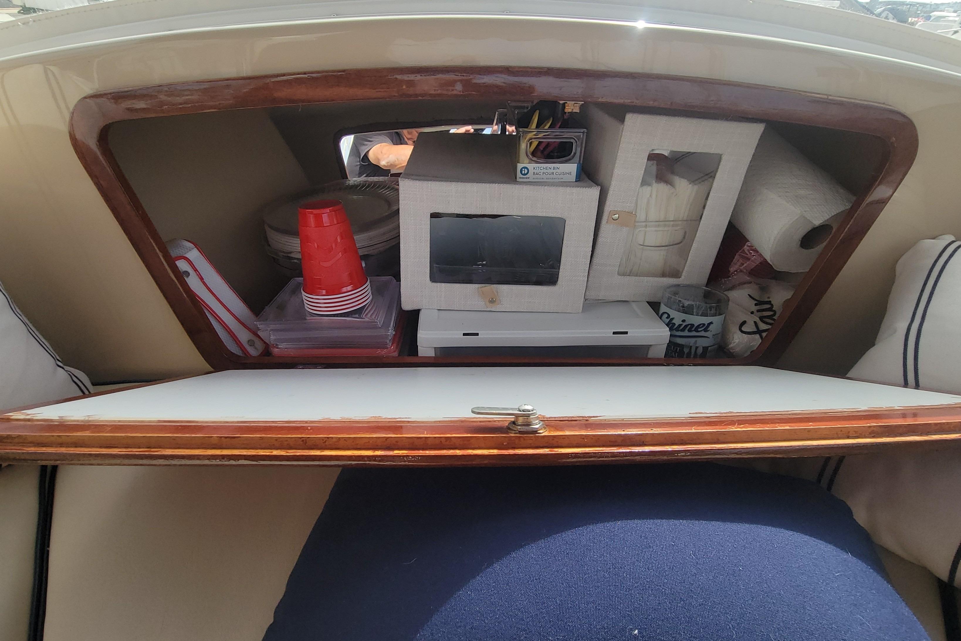 Storage compartment in a 2008 Duffy Snug Harbor 18 boat, containing cups and paper towels.