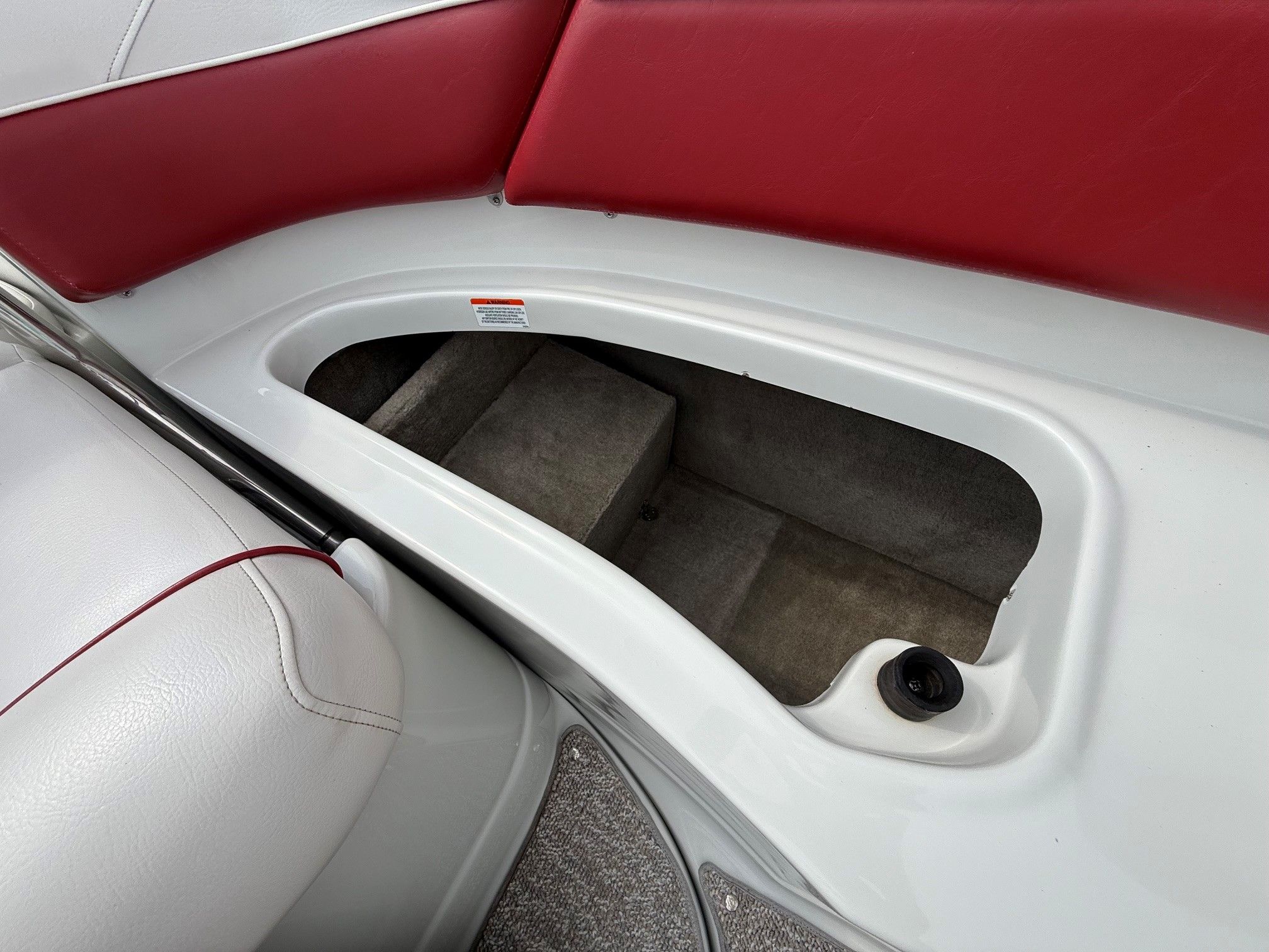 An open storage compartment on a boat with red and white upholstery.