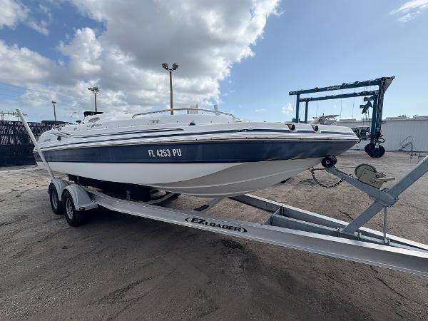 2014 Hurricane SunDeck Sport 232 OB boat on trailer under cloudy sky.