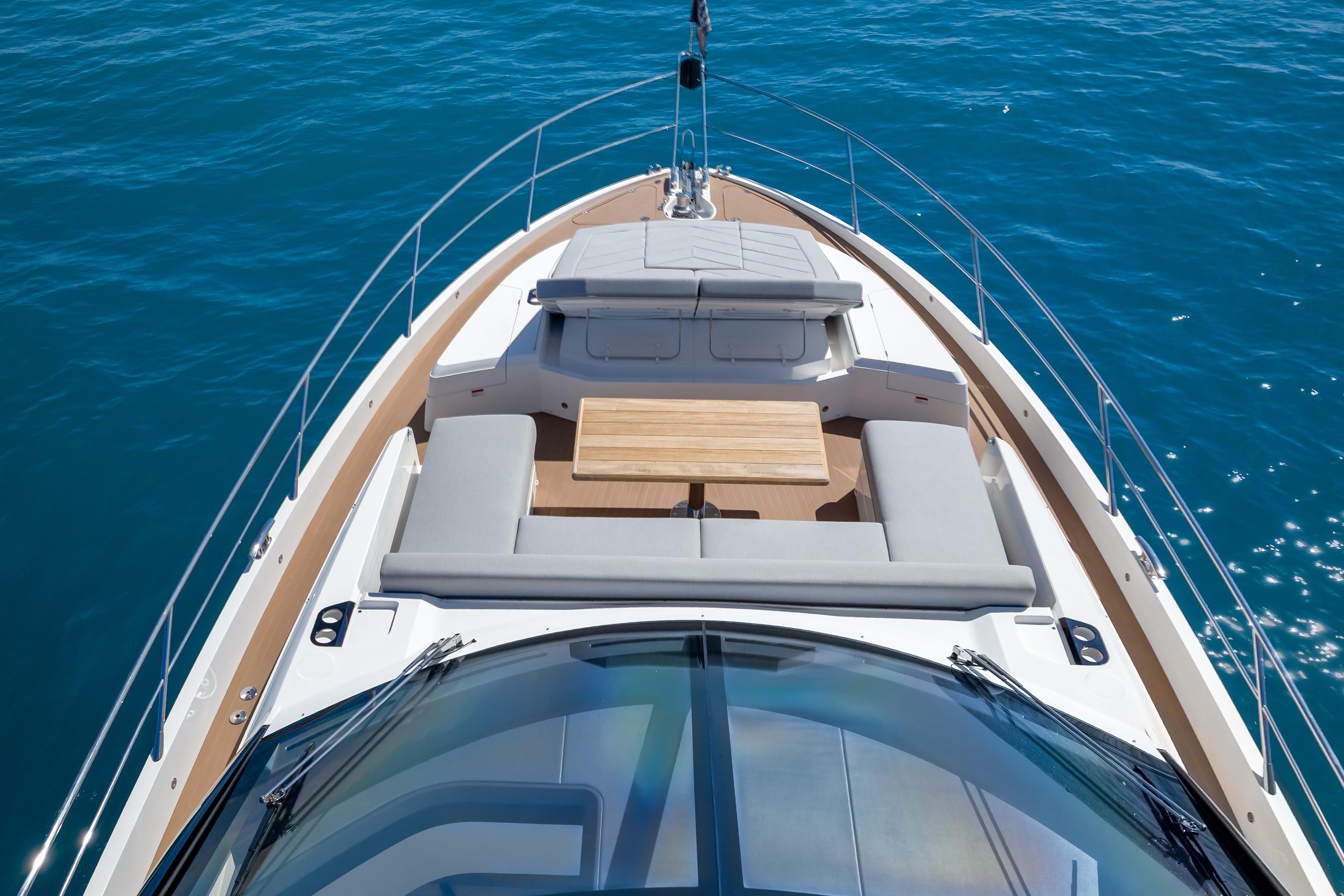 2024 Sunseeker 75 Sport Yacht deck with seating and table on blue ocean.