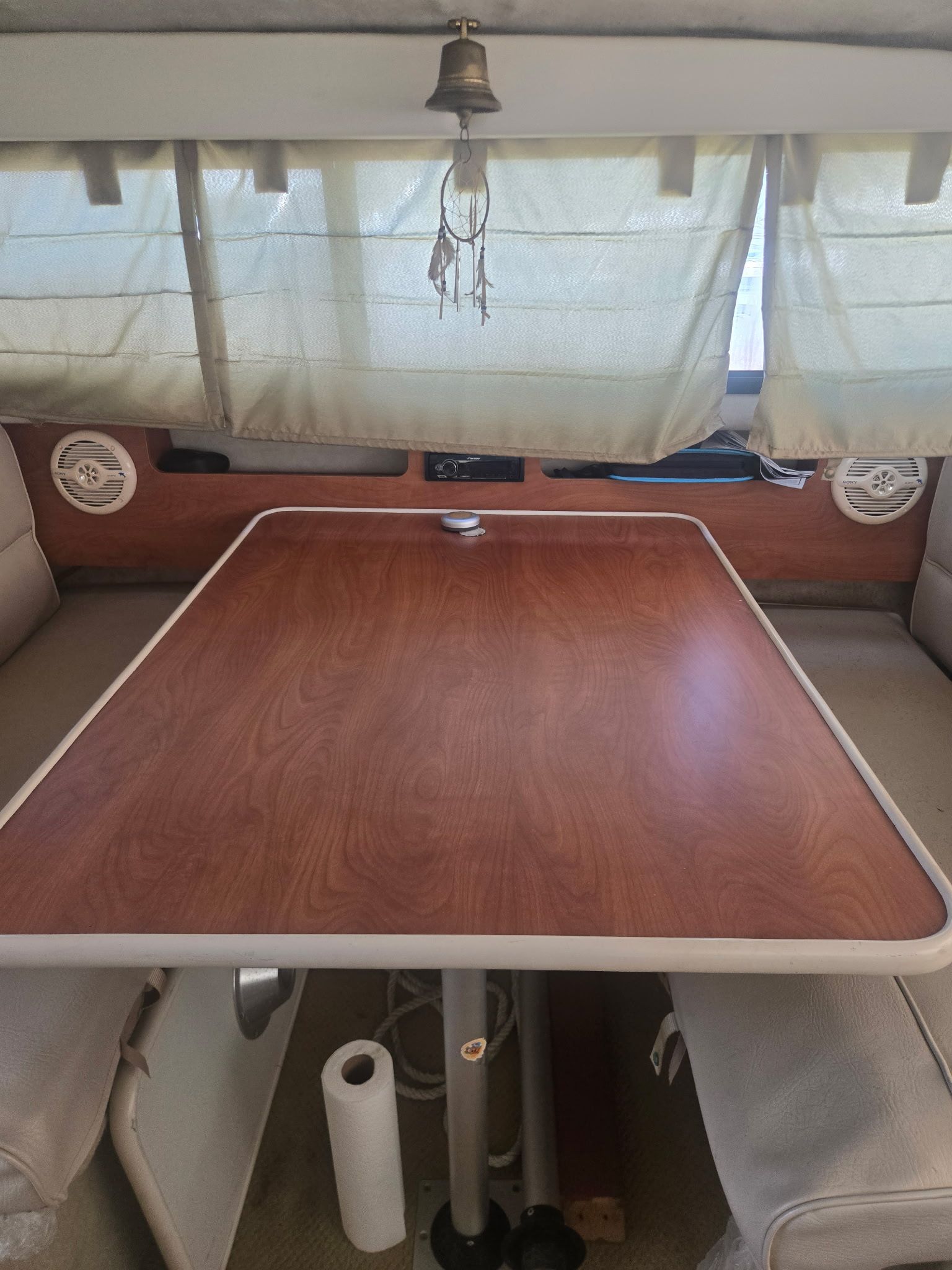 Interior of a 2003 Bayliner 28 with wooden table and curtains.