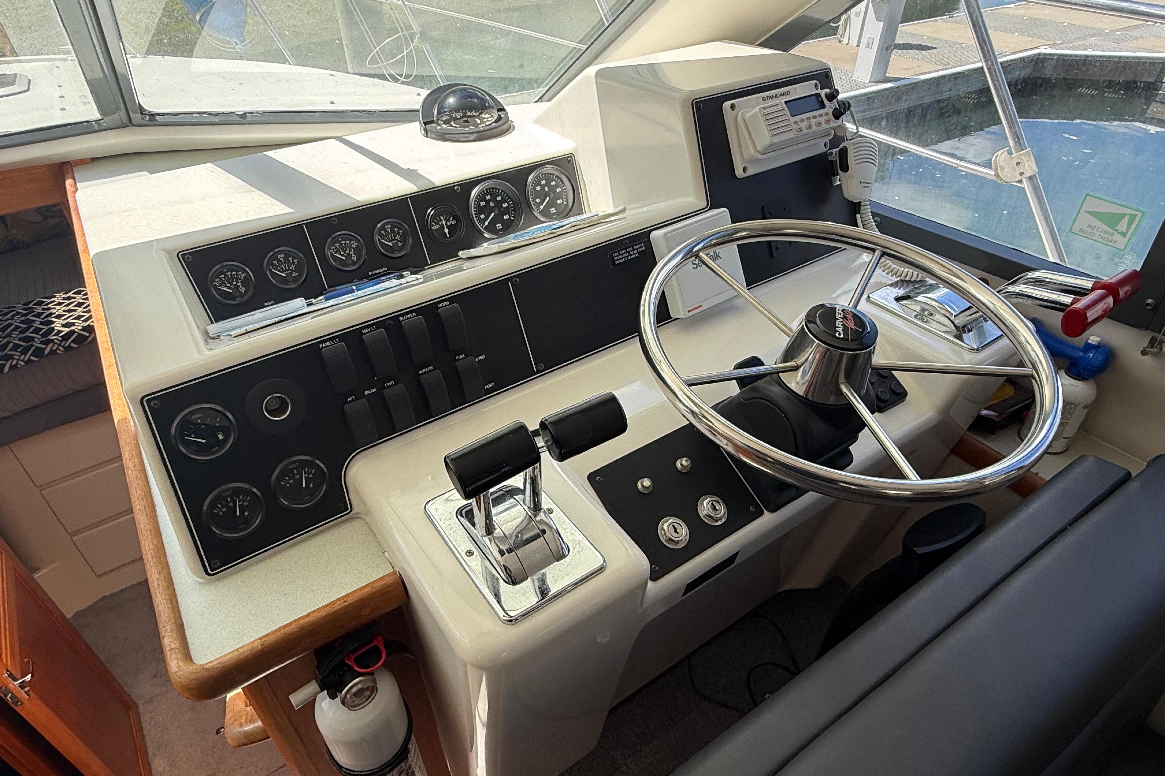 Control panel of a 1995 Carver 370 Voyager boat with steering wheel and gauges.