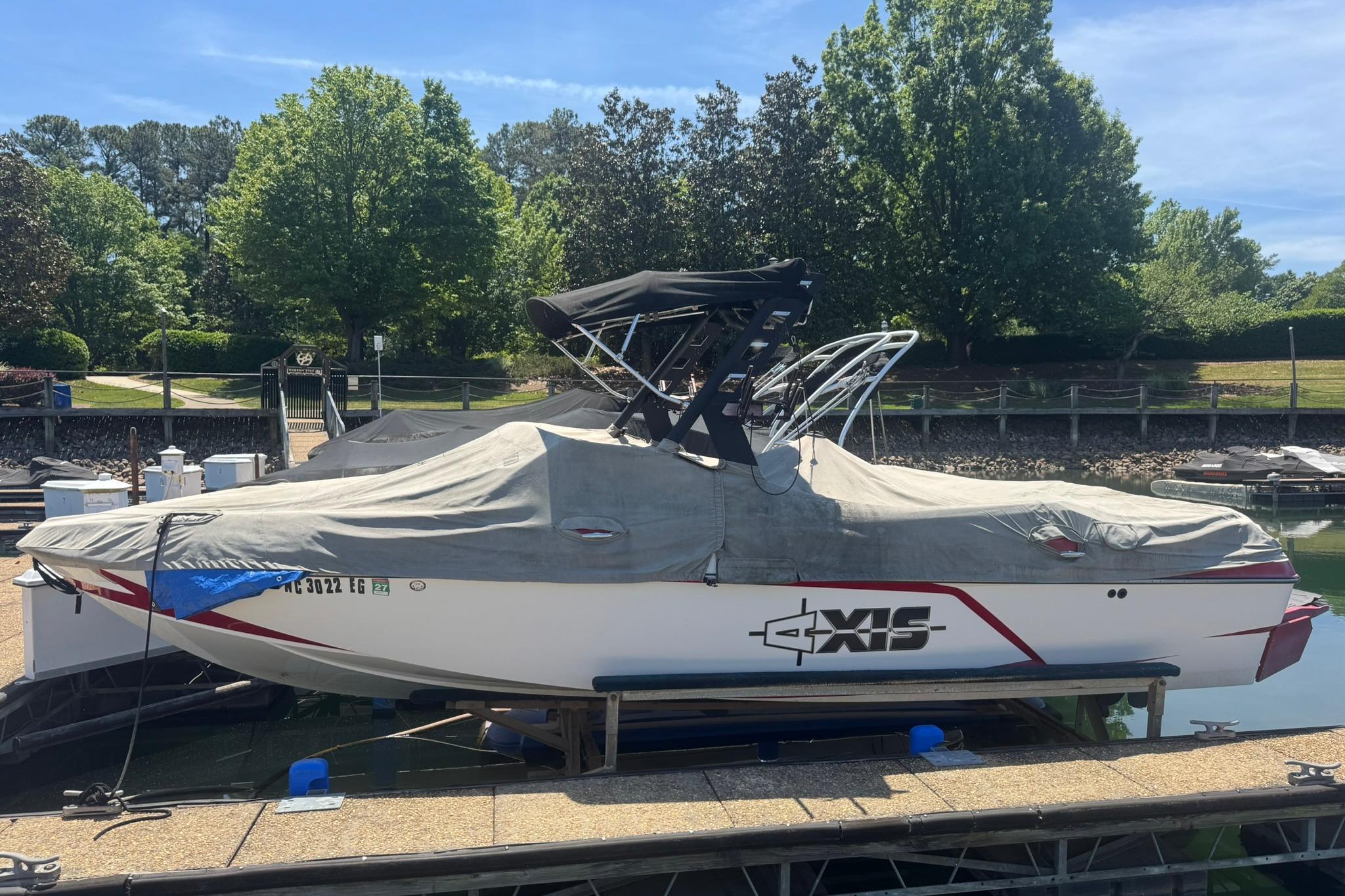 2017 Axis T23 boat covered at dock, surrounded by lush greenery.