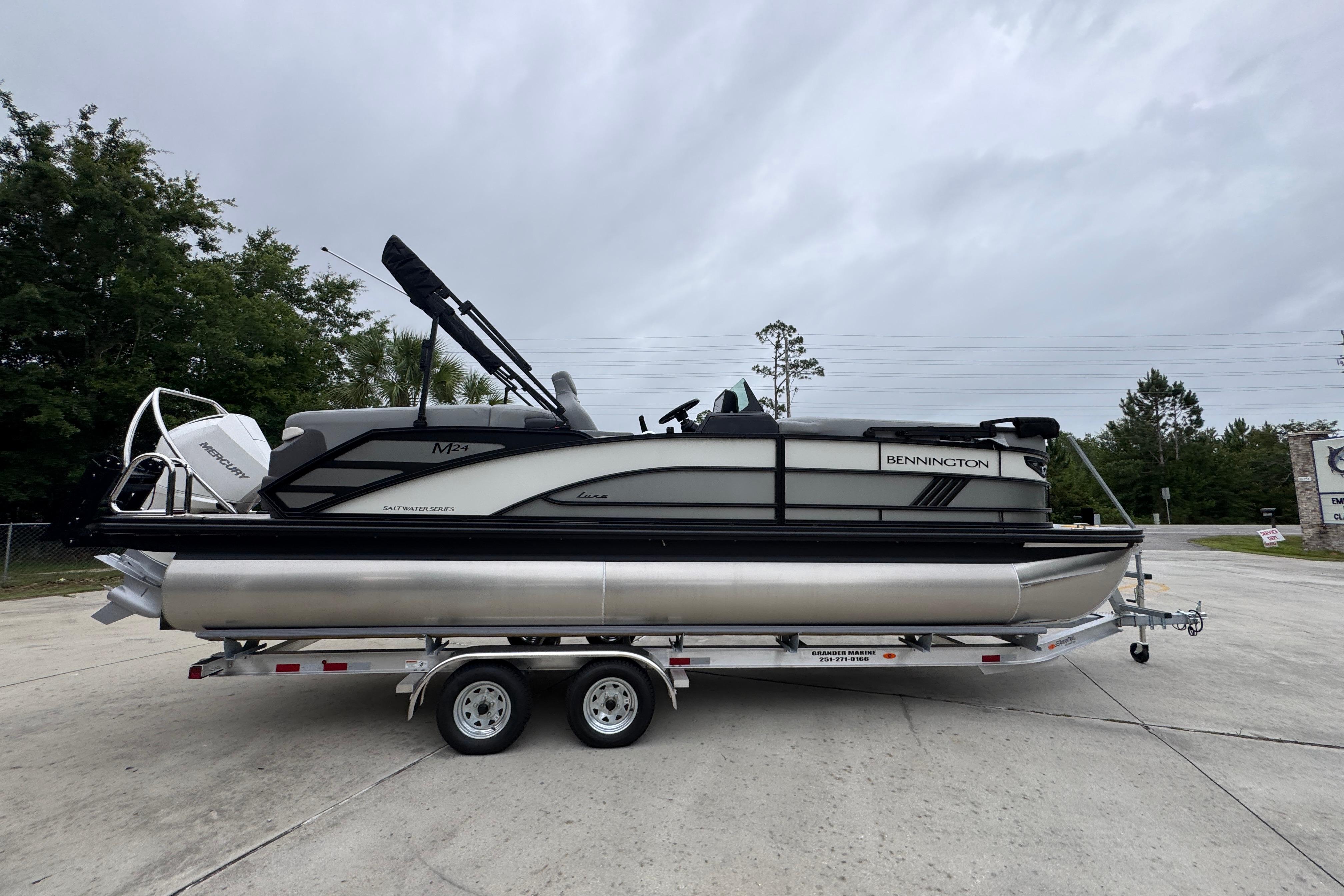 2027 Bennington 24 MFB pontoon boat on trailer, parked outdoors under cloudy sky.