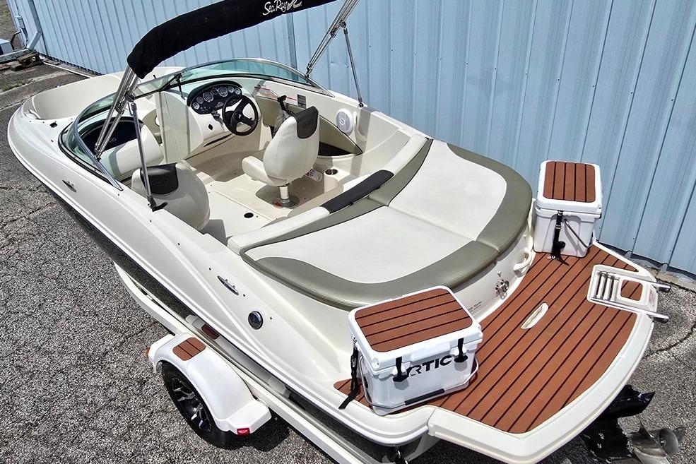 2006 Sea Ray 185 Sport boat with seating and coolers, docked near a blue wall.