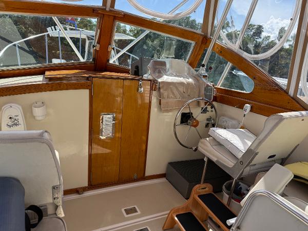 1978 Dyer 29 Trunk Cabin interior with wooden helm, steering wheel, and seating.