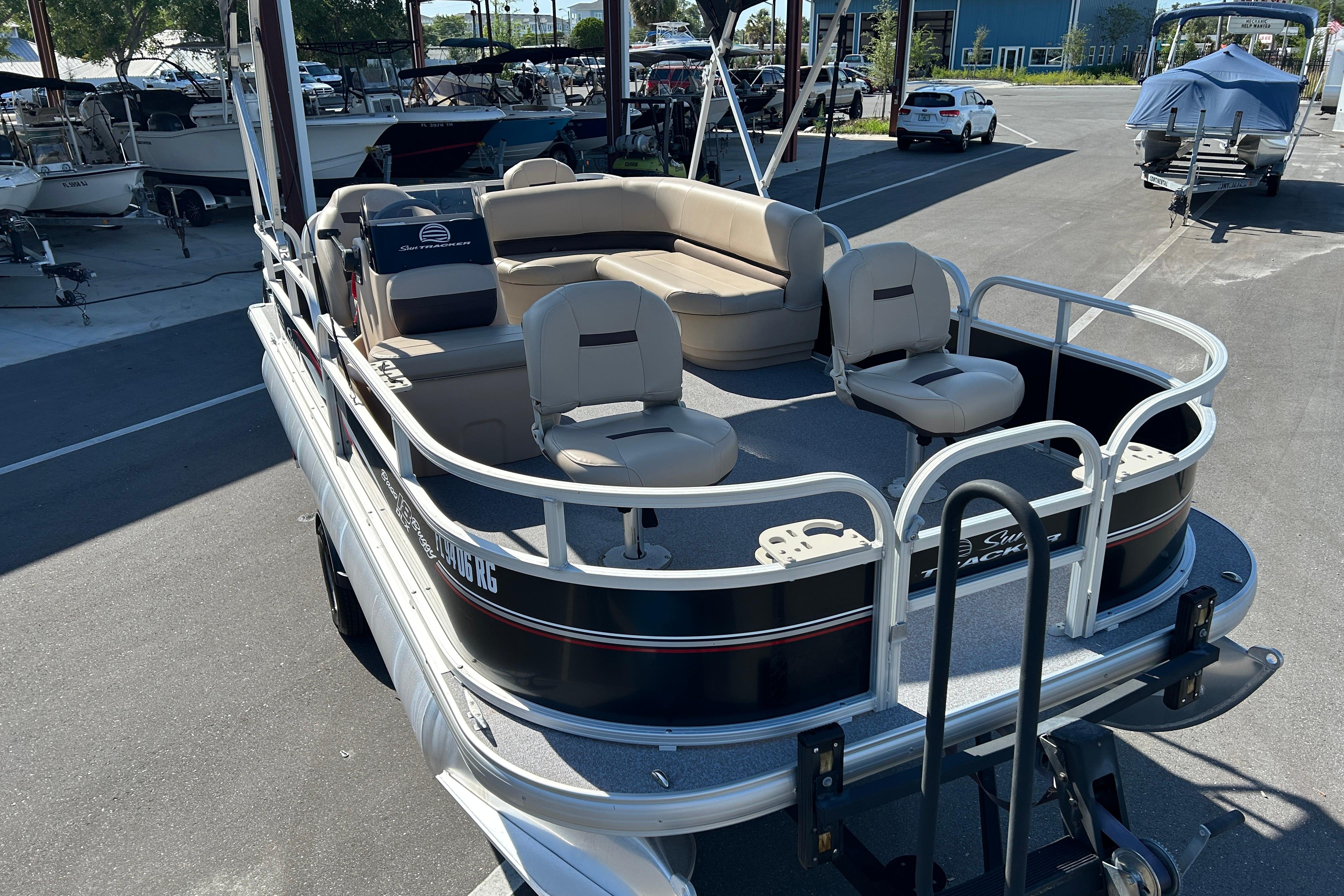 2017 Sun Tracker Bass Buggy 18 DLX pontoon boat with beige seating in a marina.