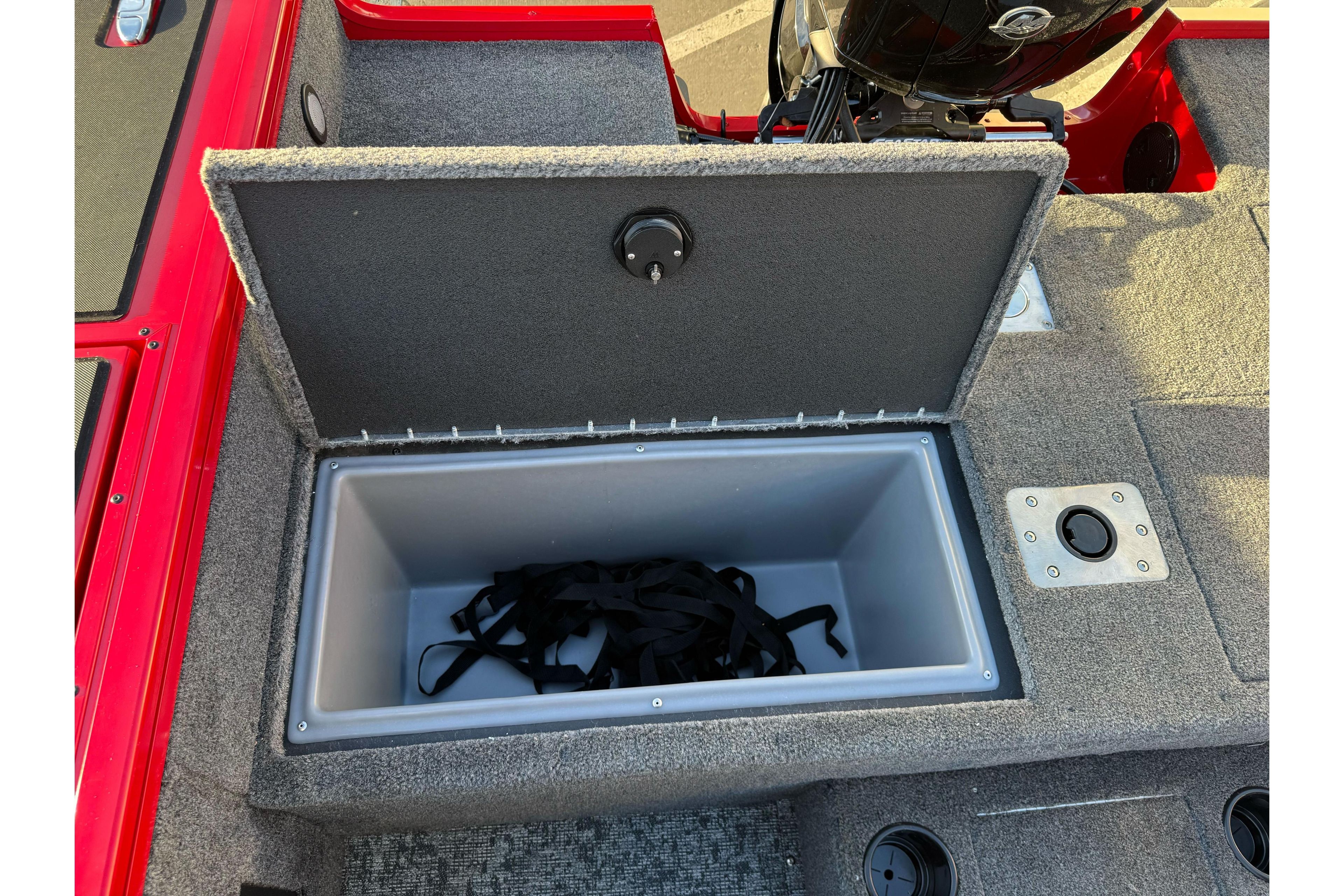 Open storage compartment in 2026 Tracker Targa V-18 WT boat, featuring gray interior and black straps.