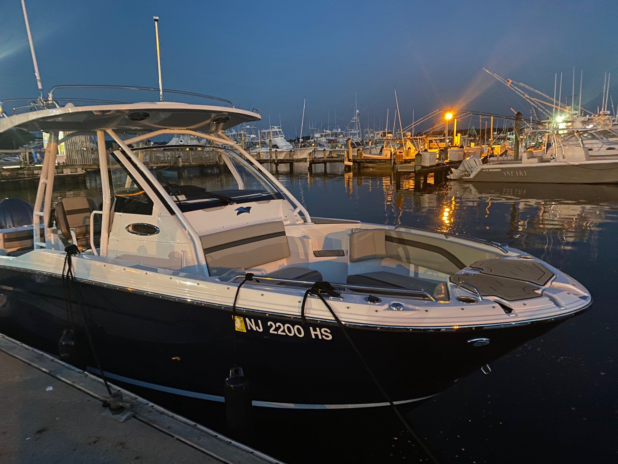 A 2022 Cutwater C-24 CW boat docked in a lit harbor at dusk.