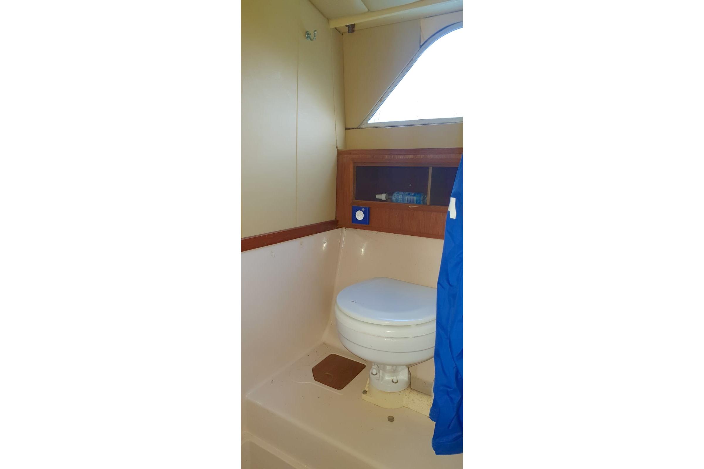 Interior of 1989 Fairey Spearfish MKIII boat bathroom with toilet and storage shelf.