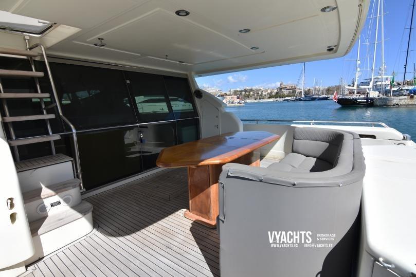 Outdoor seating area on a 1997 Ferretti Yachts 70, overlooking a marina.
