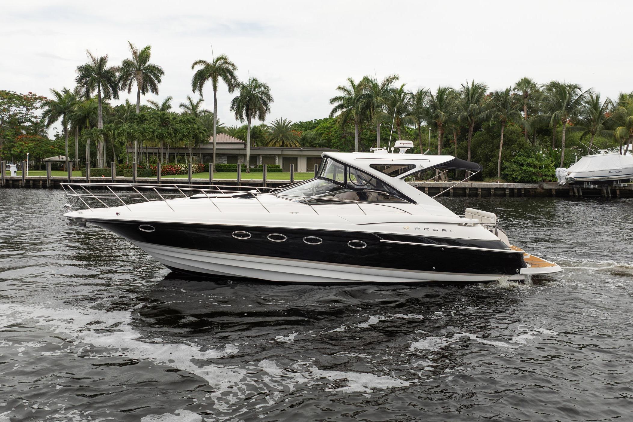 2008 Regal Commodore 4460 yacht cruising on a tropical waterway with palm trees.