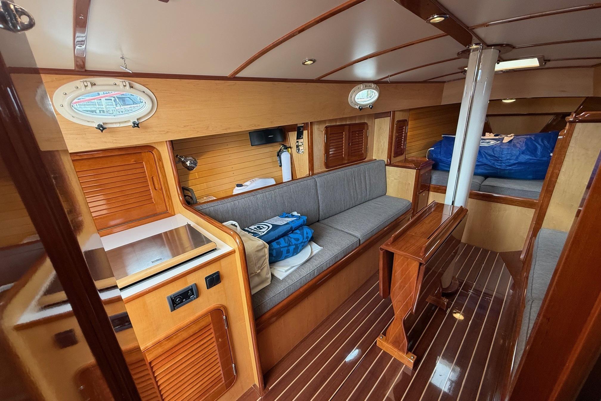 Interior of 2015 Hinckley DS 42 yacht with wooden finishes and cozy seating area.