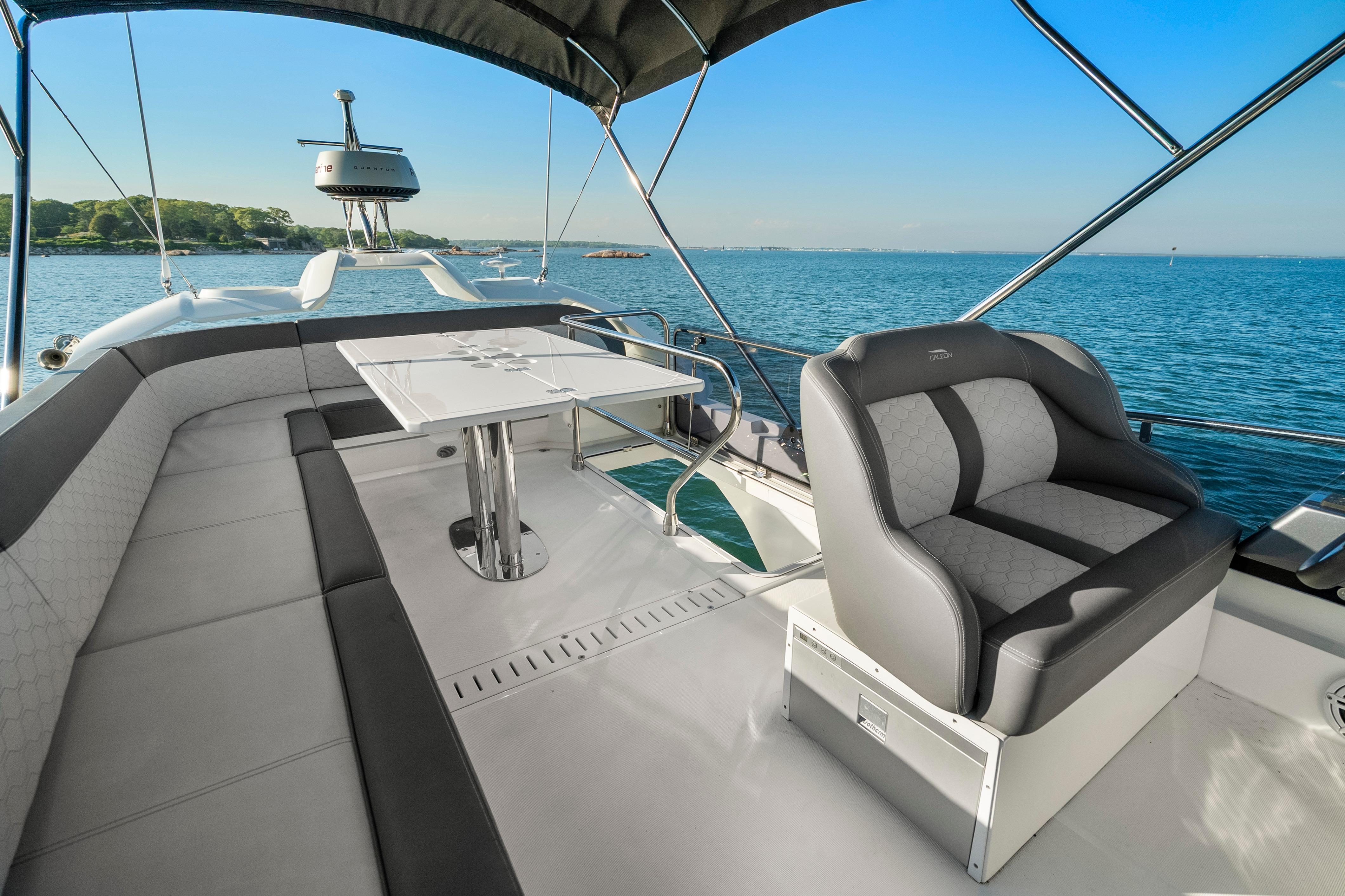 2023 Galeon 400 Fly yacht flybridge with seating and table, overlooking serene ocean view.