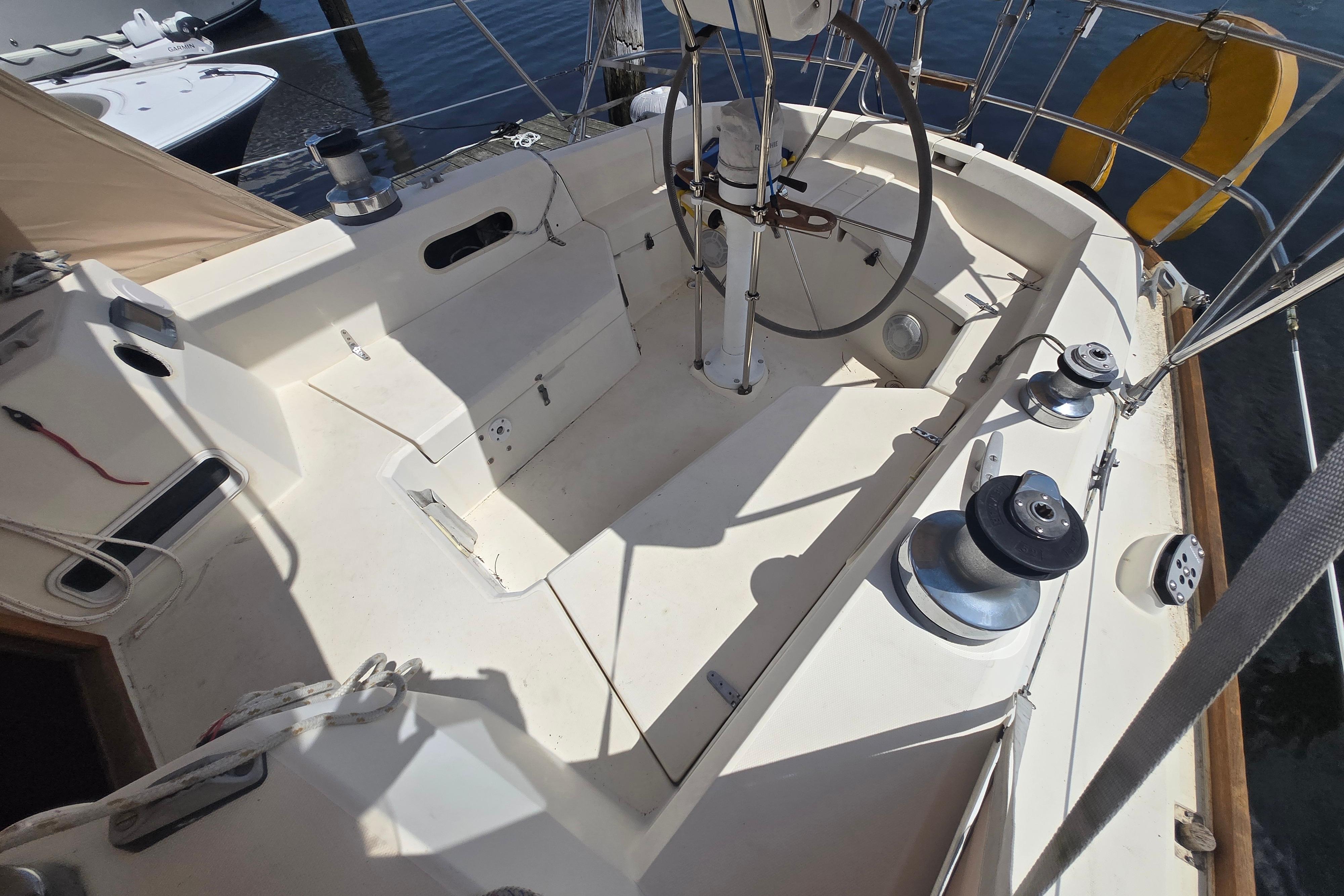 Cockpit of 1988 Sabre 38 sailboat with steering wheel and winches, docked at marina.