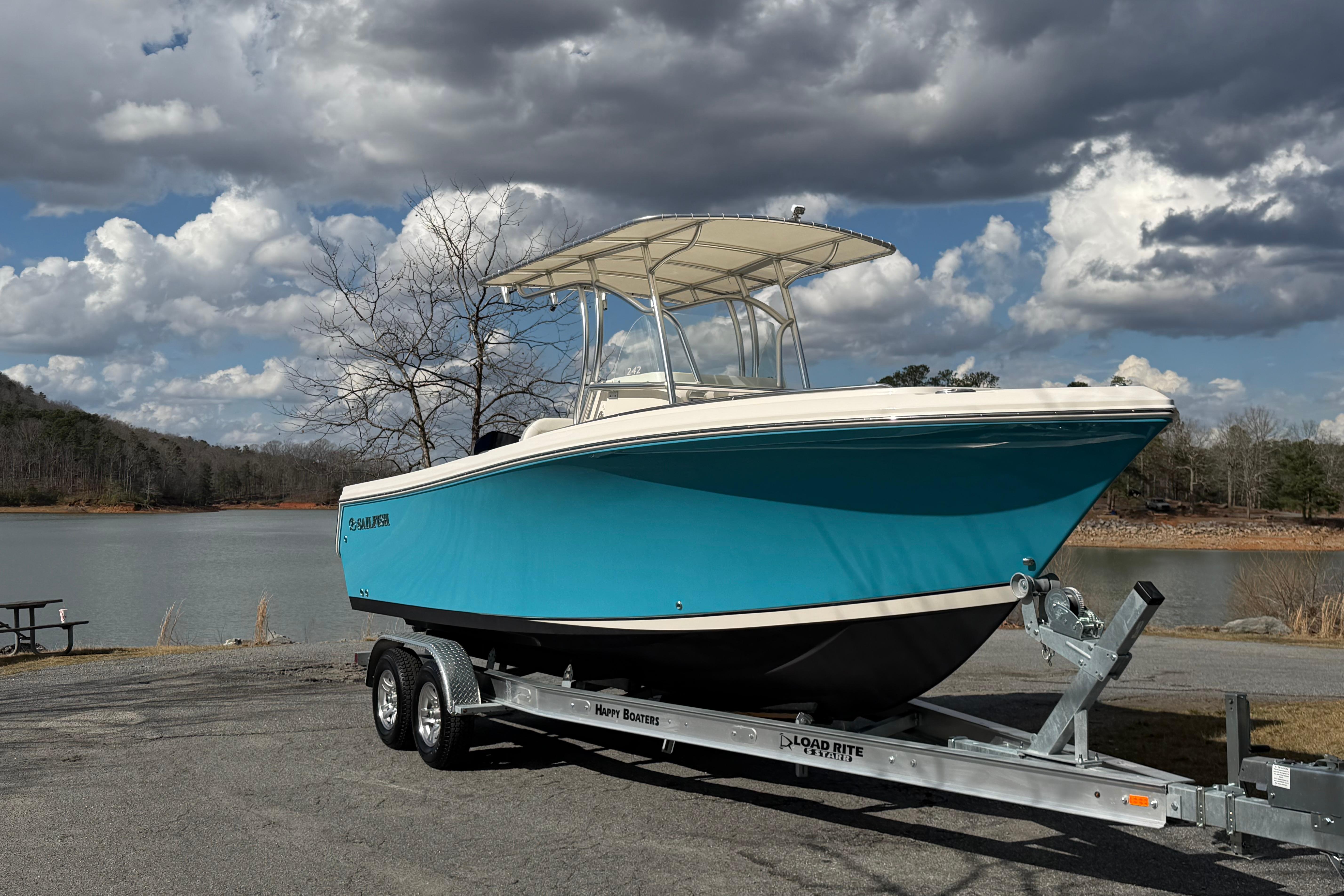2022 Sailfish 242 CC boat on trailer by a scenic lake under cloudy sky.