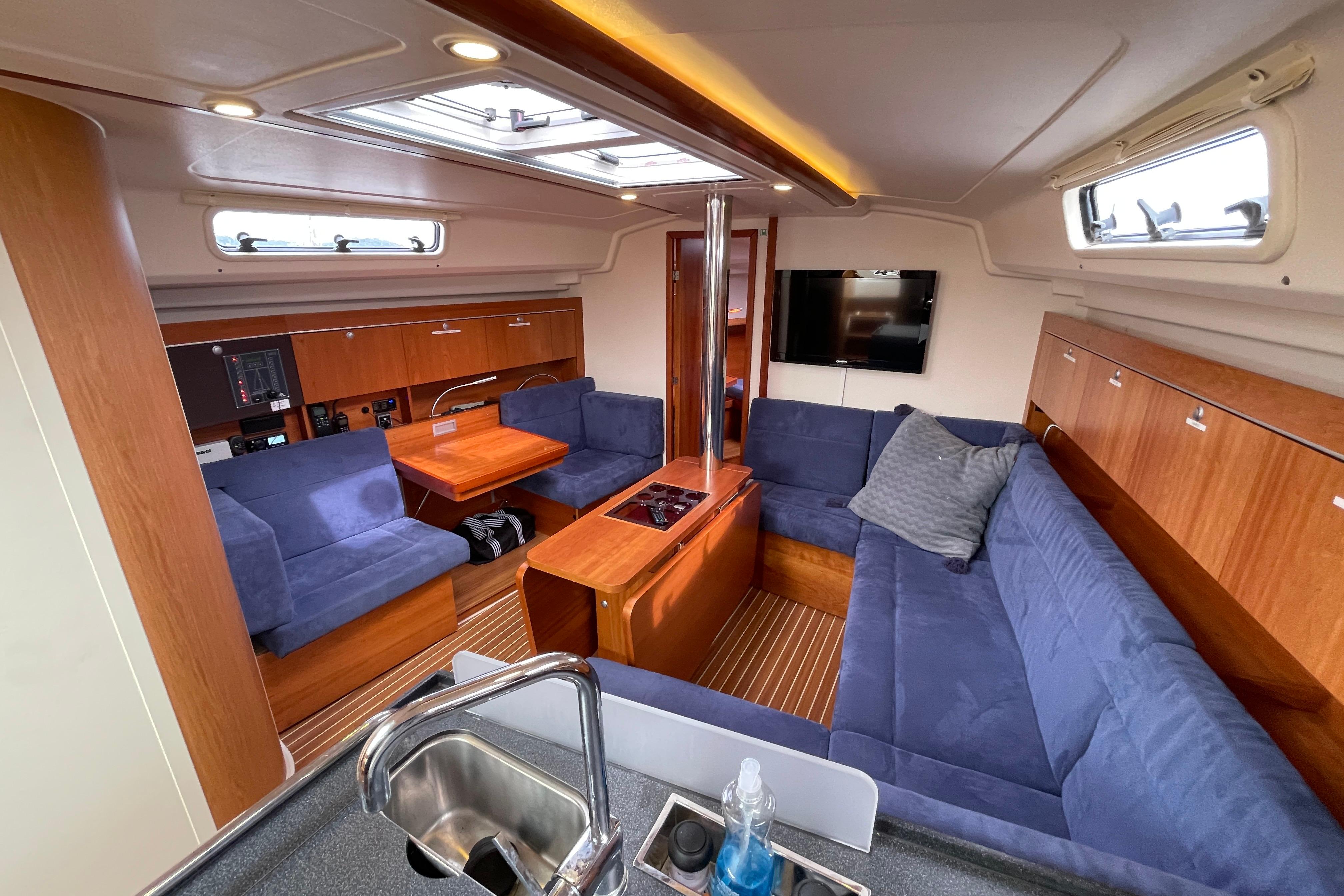 Interior of 2014 Hanse 415 yacht with blue seating, wooden cabinetry, and modern amenities.