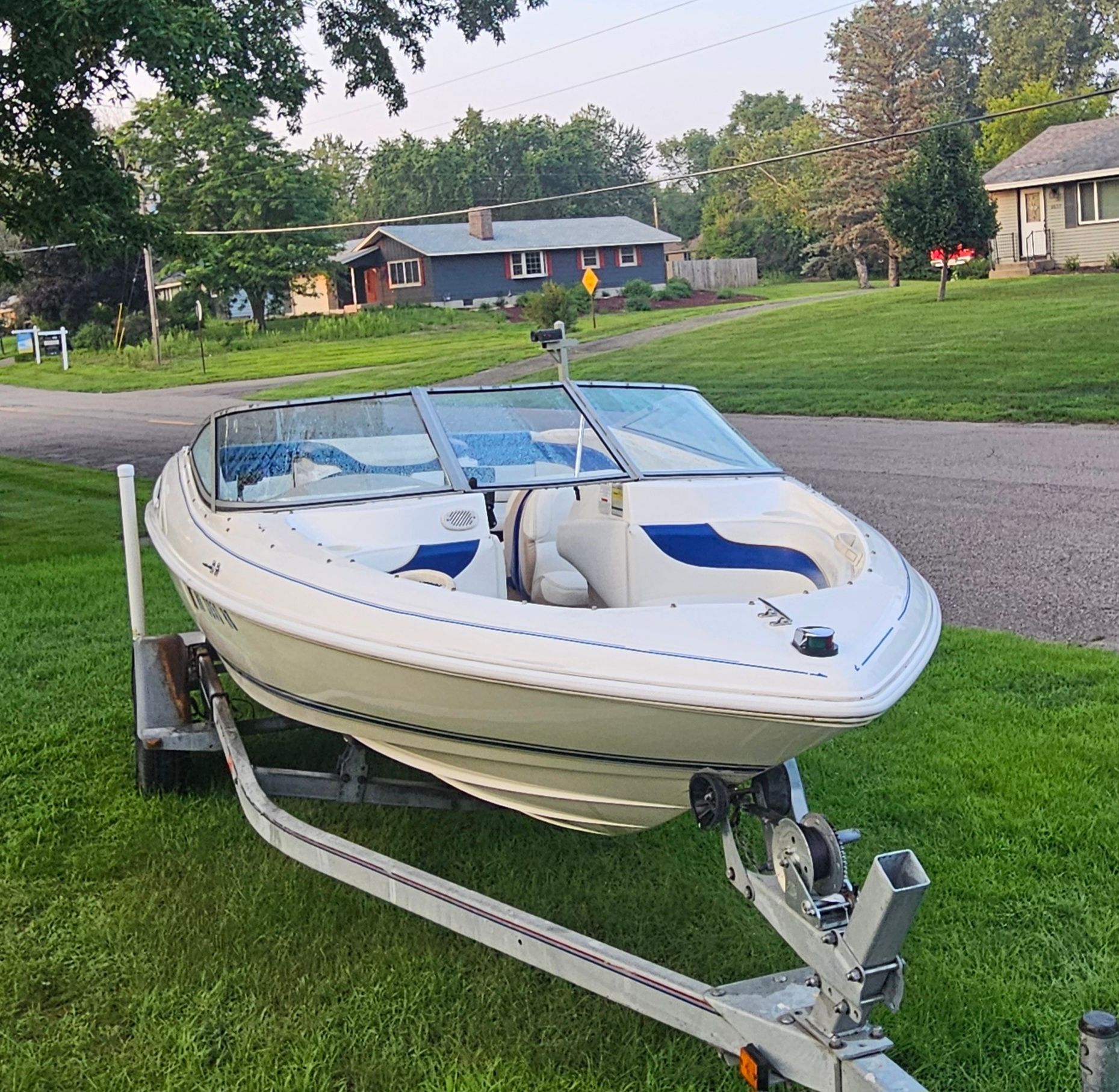 A 1996 Wellcraft Excel boat on a trailer, parked on a grassy lawn.