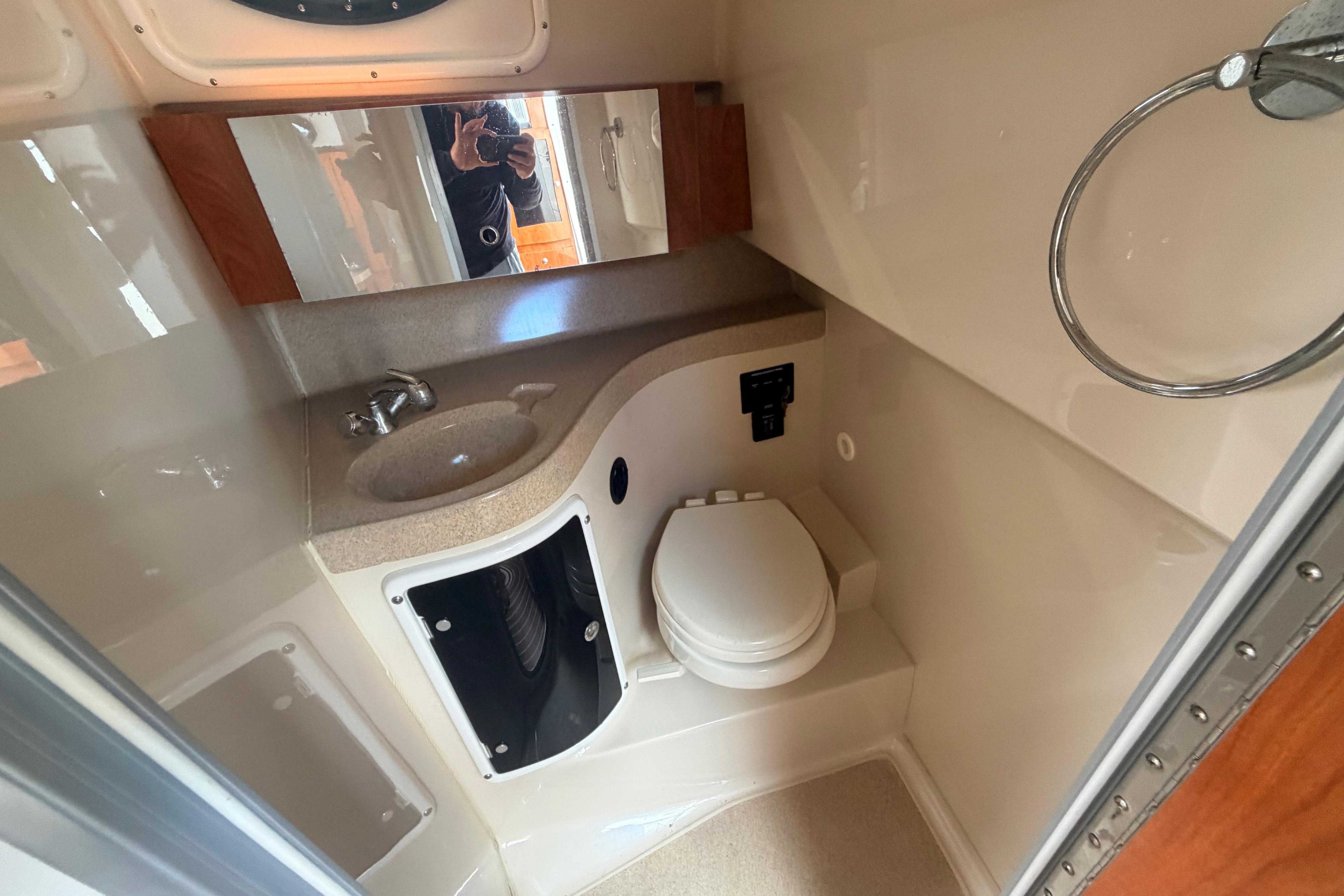 2015 Wellcraft 290 Coastal boat bathroom with sink, toilet, and mirror.