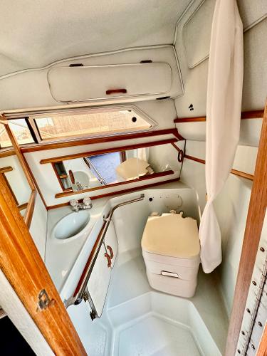 1987 Sea Ray 270 Sundancer bathroom with sink, mirror, and compact toilet.