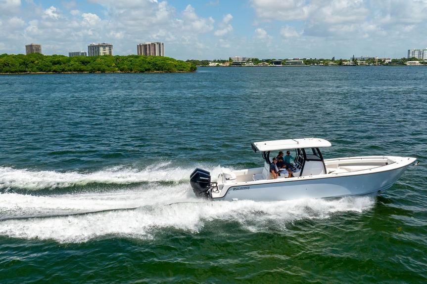 2027 Reef Runner 340 boat cruising on a sunny day near a city shoreline.