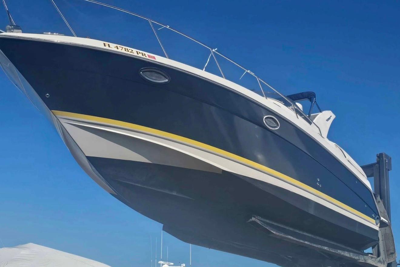 2003 Regal Commodore 3260 boat lifted against clear blue sky.