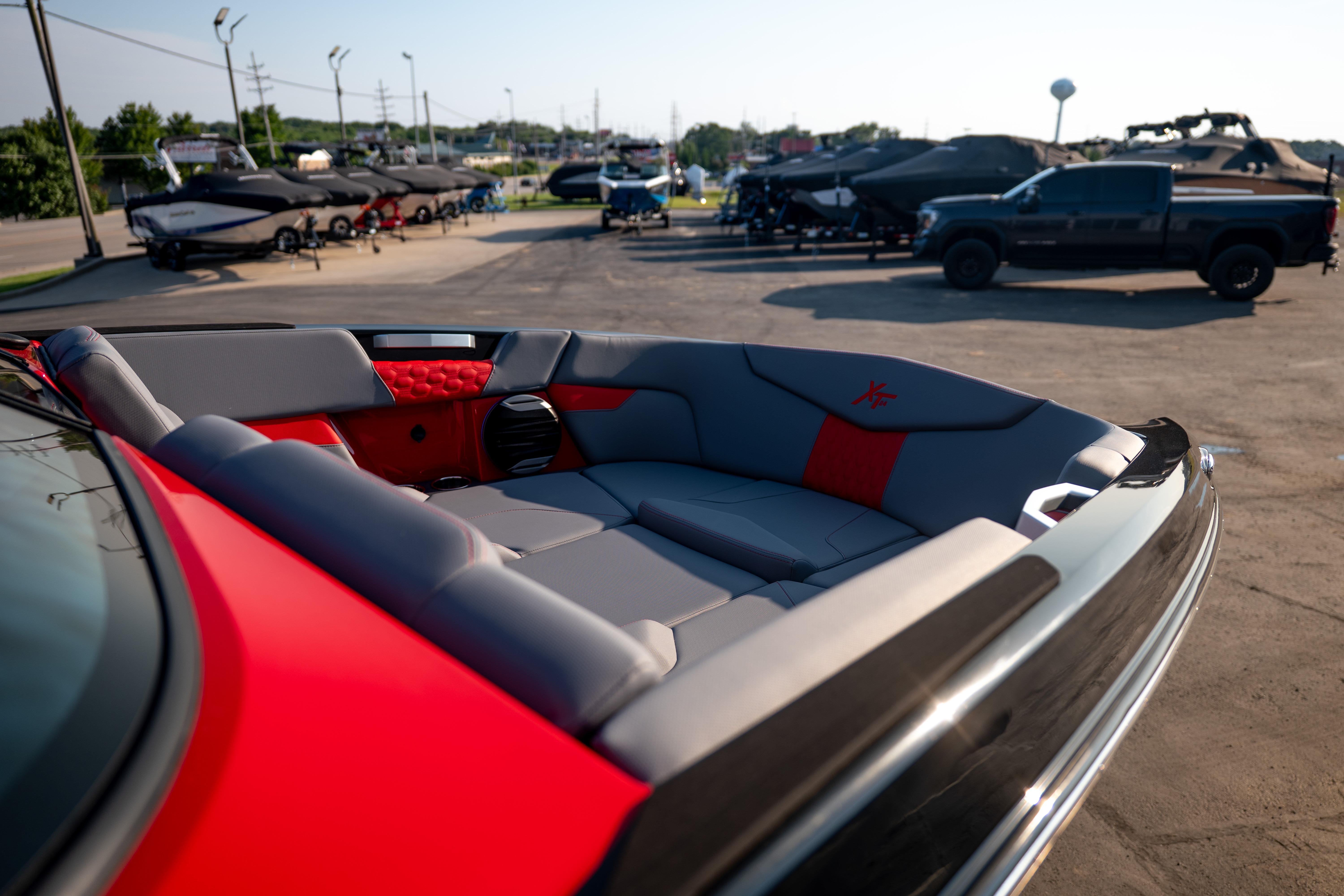 2027 MasterCraft XT24 boat interior with red and gray seating, parked outdoors.