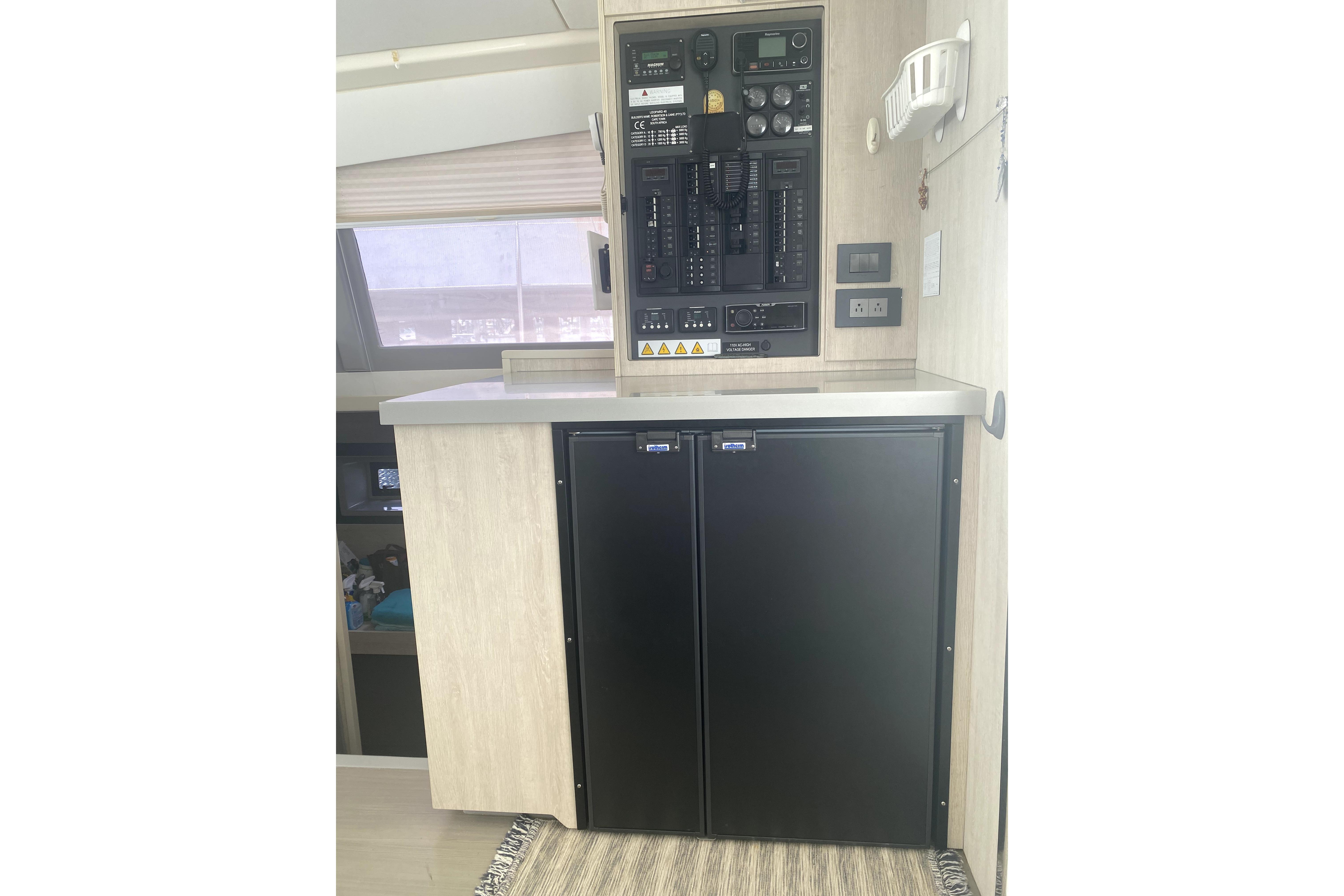 Interior of a 2017 Leopard 40 yacht featuring control panel and compact refrigerator.
