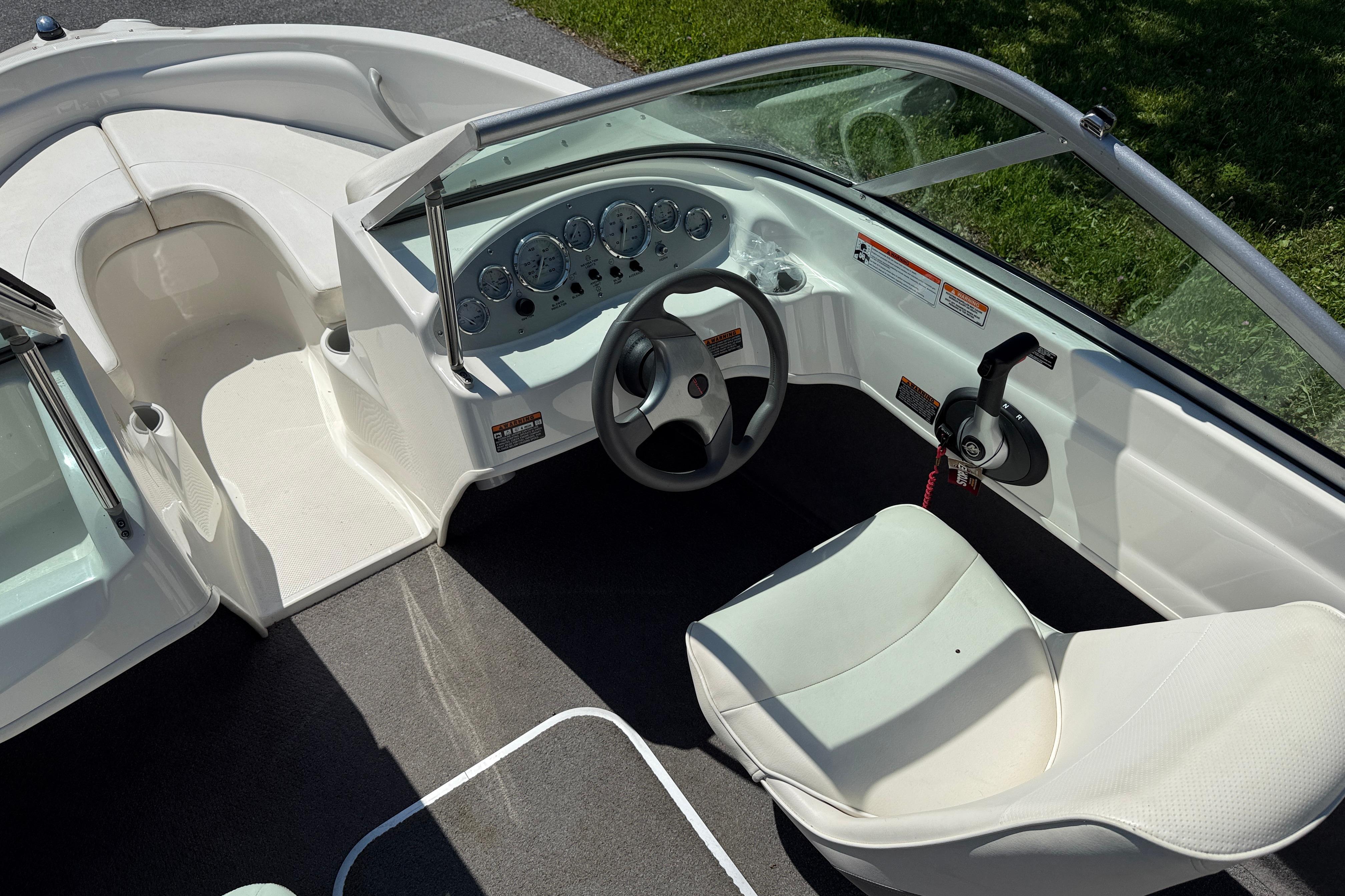 2009 Bayliner 175 boat interior with steering wheel and dashboard, featuring white seating and carpeted floor.