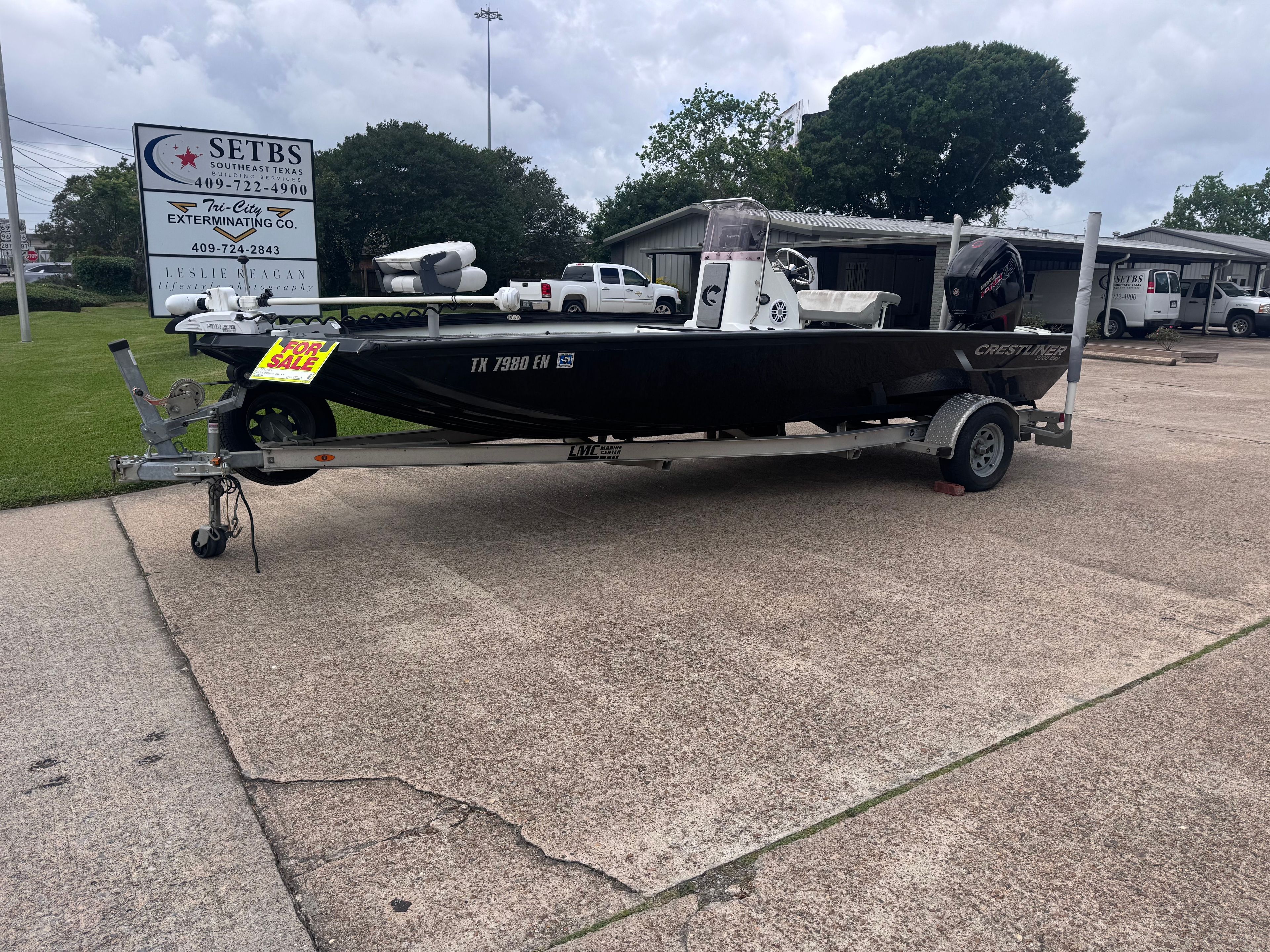 A black 2019 Crestliner 2000 Bay boat on a trailer in a parking lot.