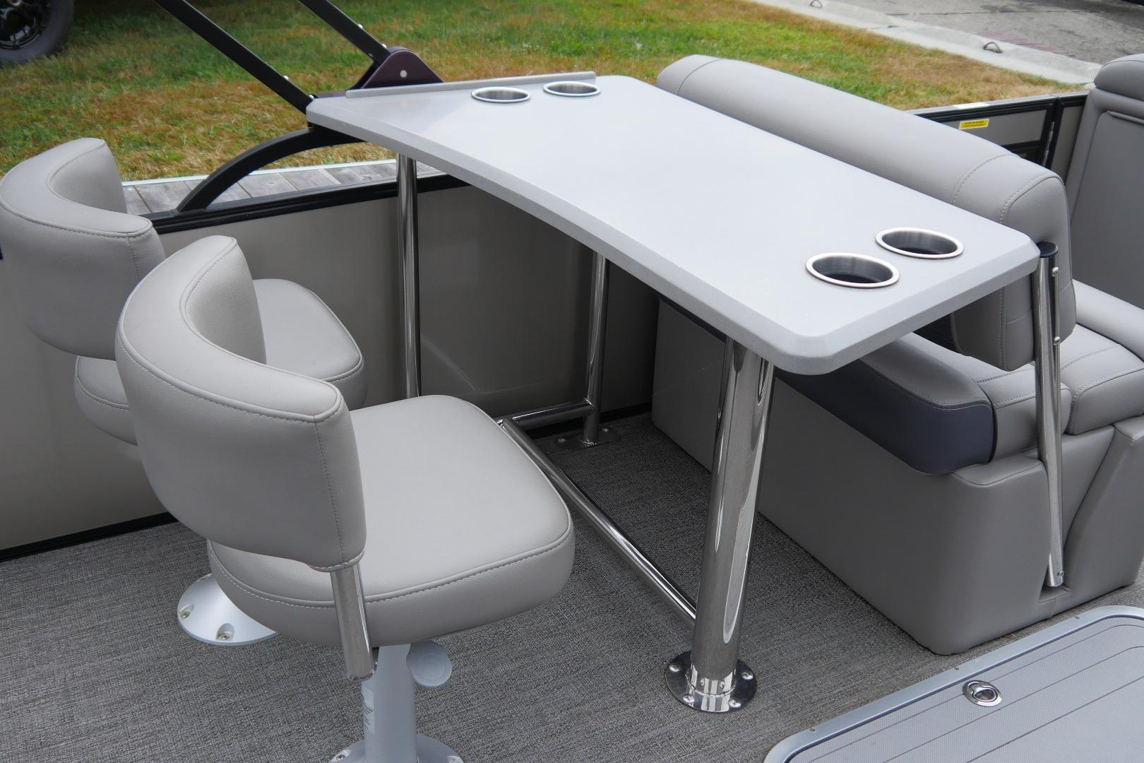 2023 Barletta CORSA 25UE boat interior with seating and table featuring cup holders.