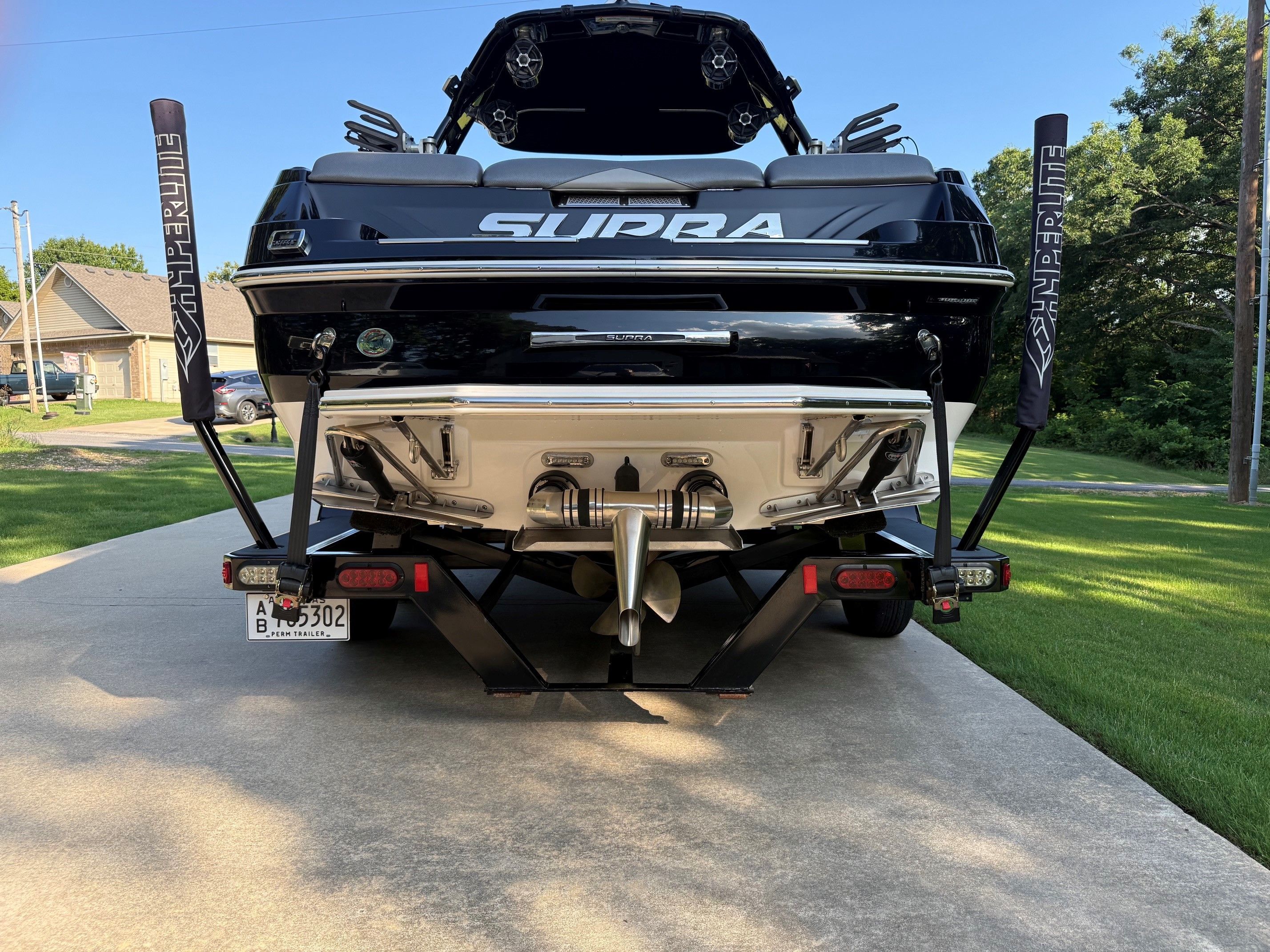 Rear view of a black Supra SC350 boat on a trailer, parked on a driveway.
