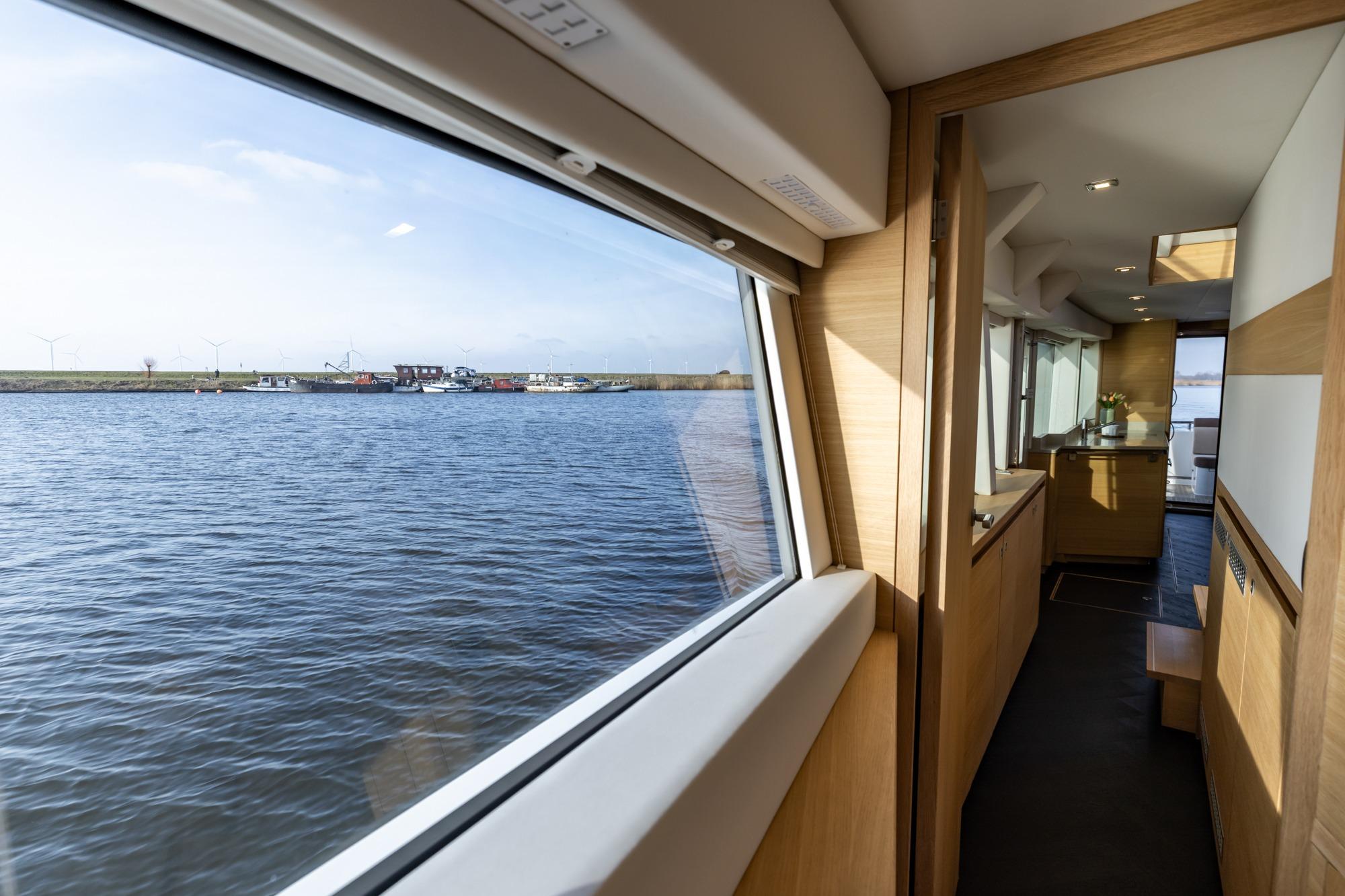 Interior view of 2017 Steeler Panorama FF 53 yacht with scenic waterway through window.