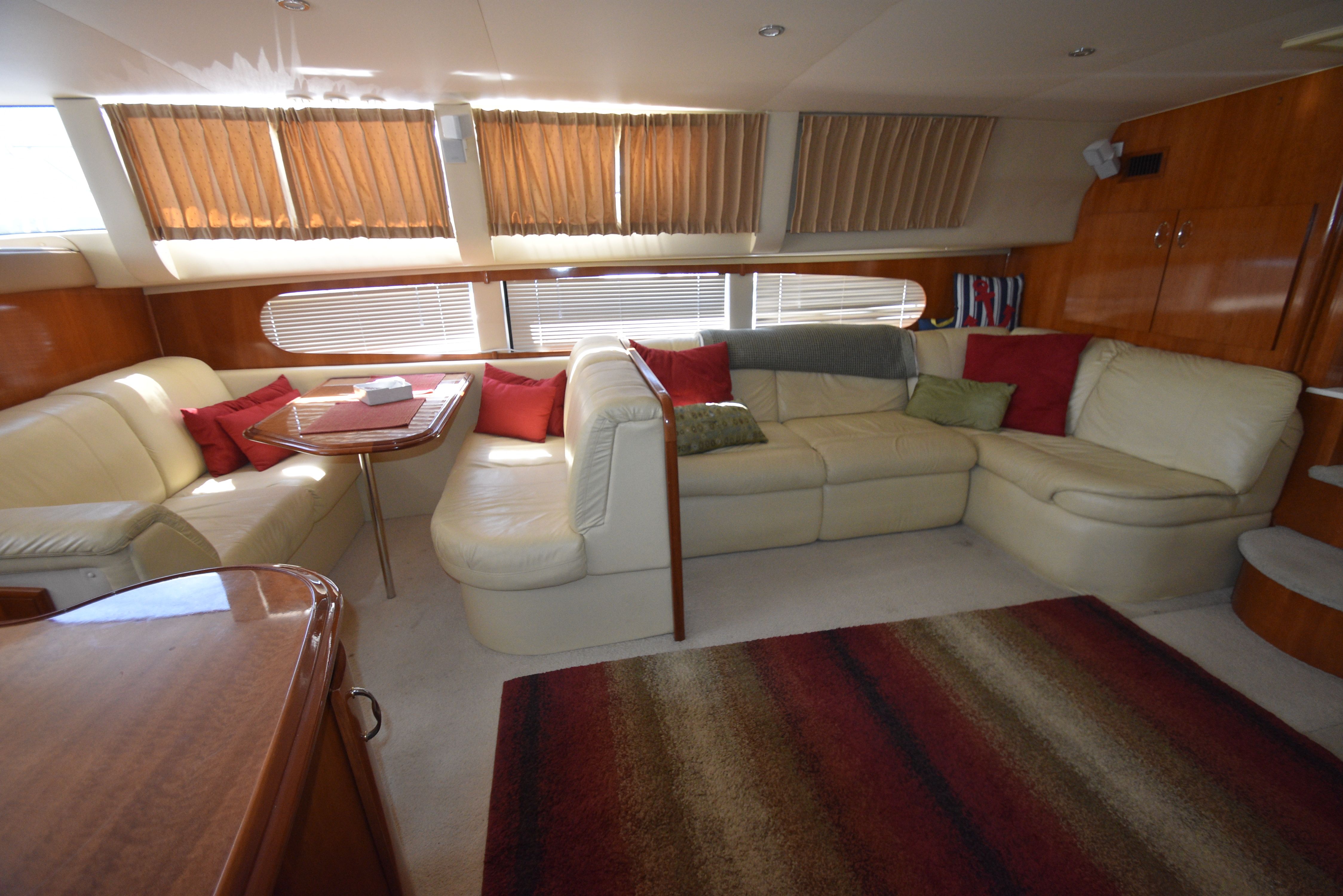 Interior of a 2004 Carver 466 Motor Yacht with beige sofas and red cushions.
