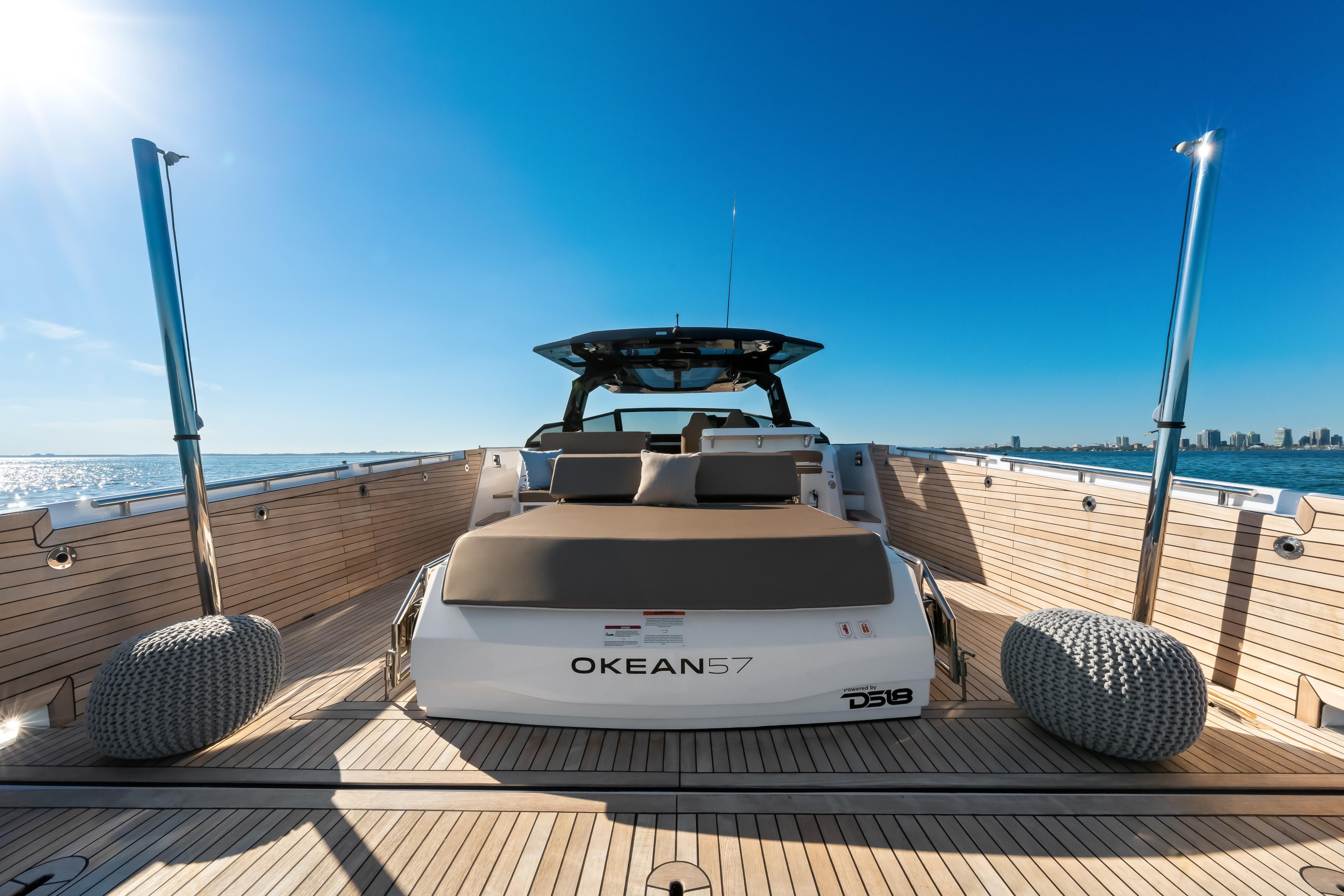 Luxury OKEAN 57 yacht, 2026 model, cruising on open water under clear blue skies.