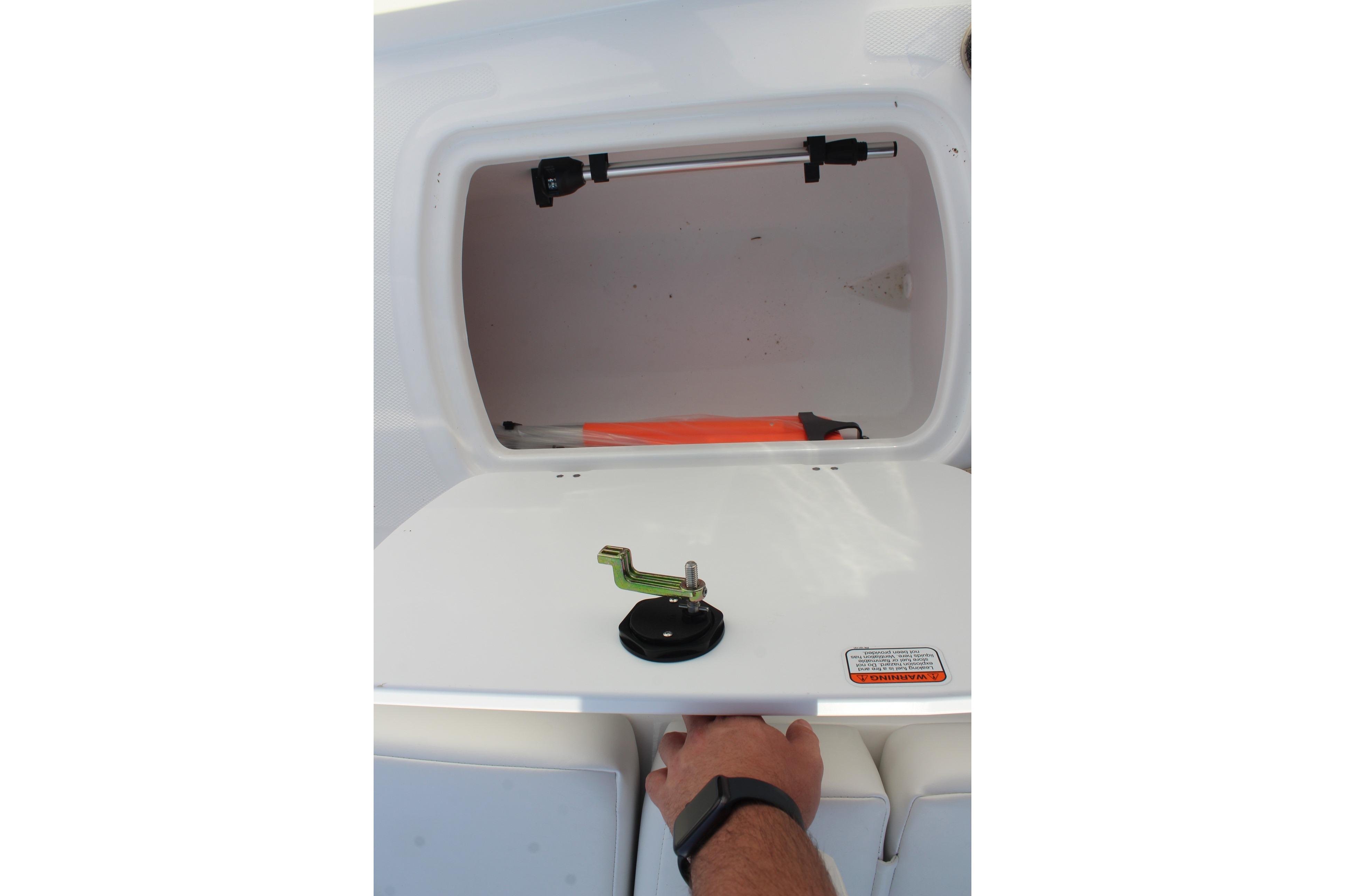 Storage compartment of 2026 Tahoe T18 boat, featuring a latch and safety warning label.