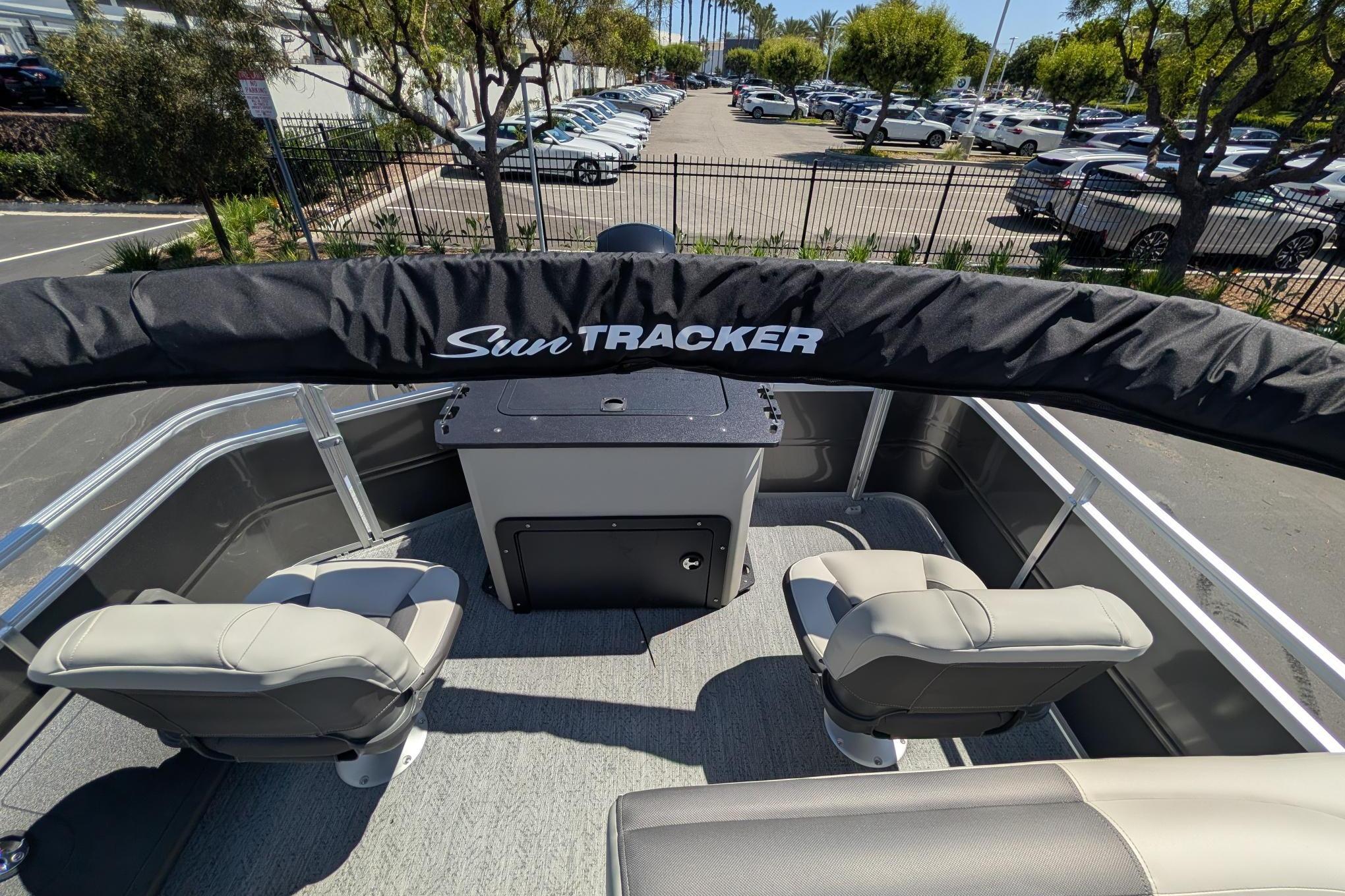 2026 Sun Tracker Fishin' Barge 22 DLX interior with seating and storage, parked outdoors.